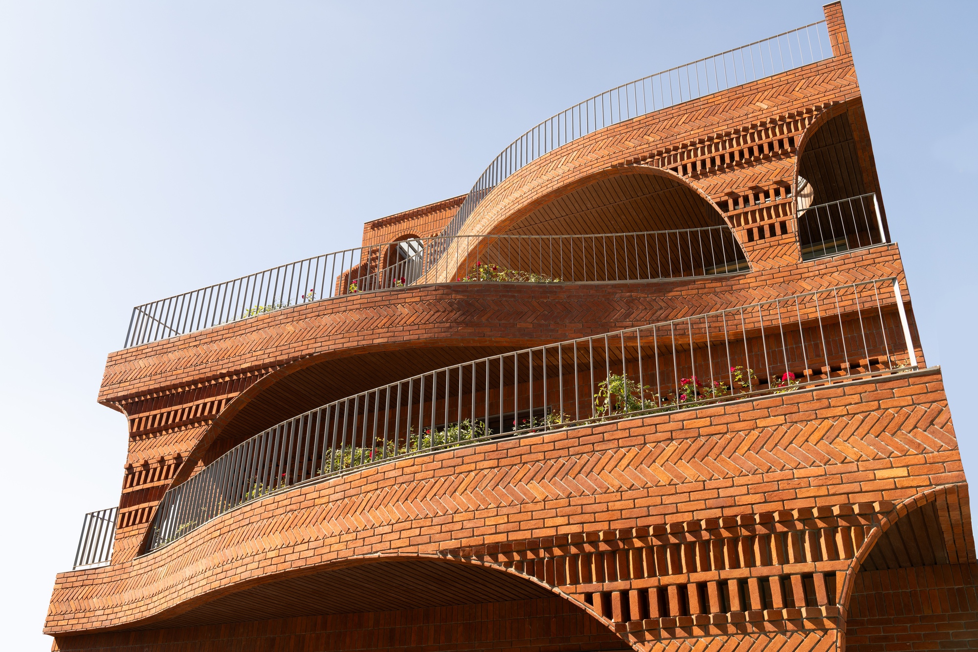 Close-up of the layered brick facade showing chevron patterns and curved balconies with metal railings