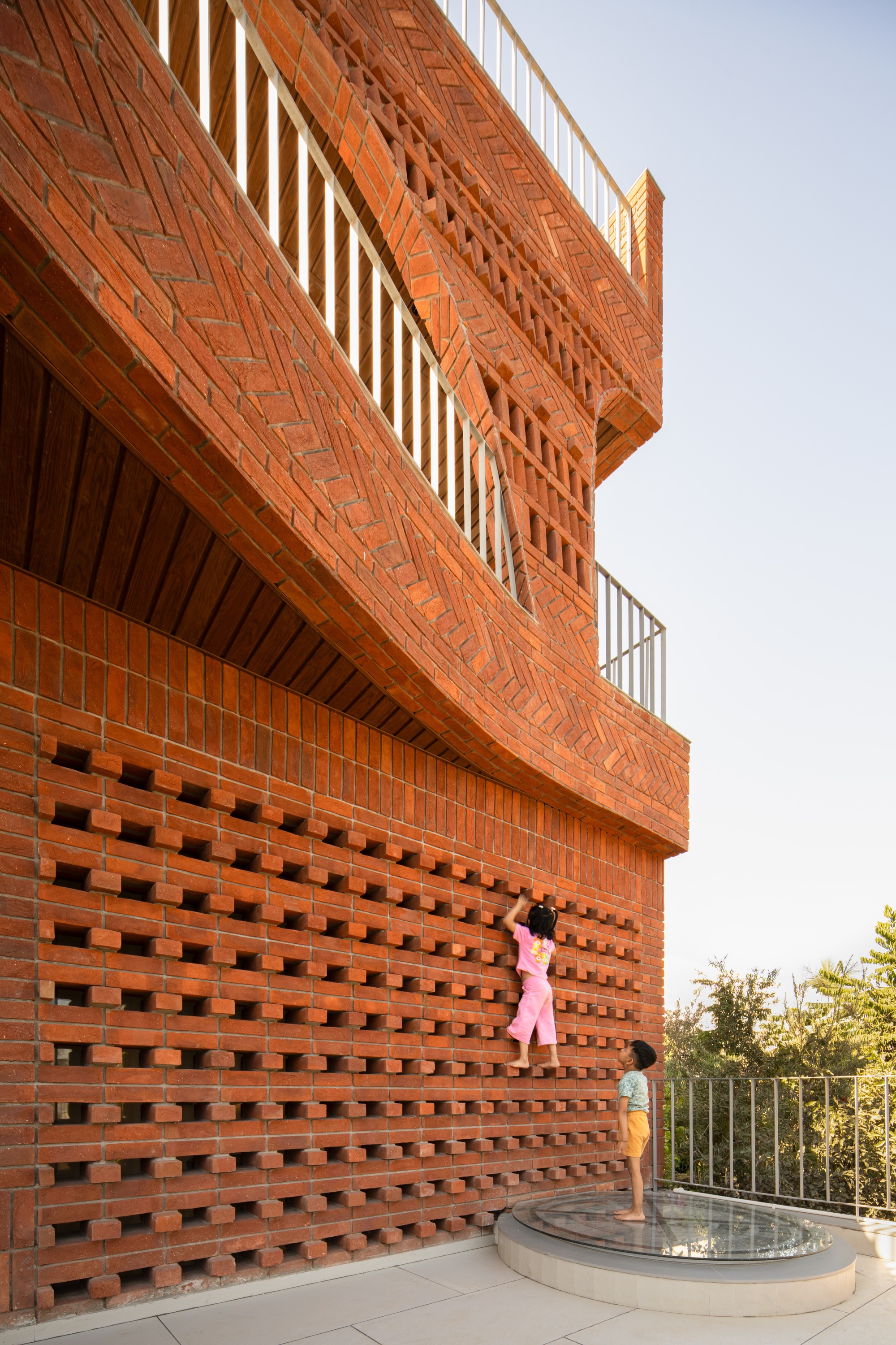 Perforated brick wall on rooftop terrace with child standing beside circular water fountain