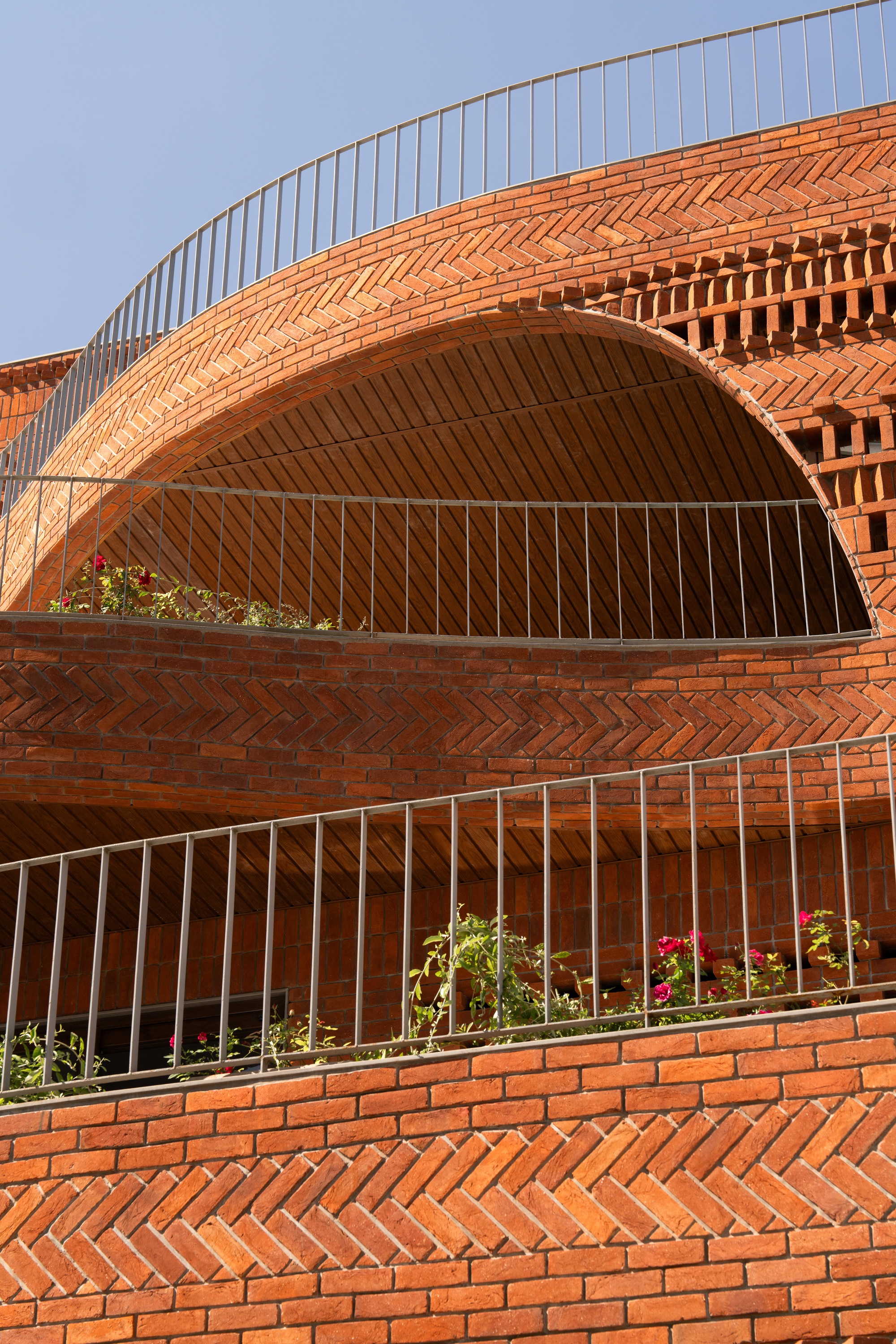 Close-up of herringbone brick arches framing balconies with potted plants and metal railings