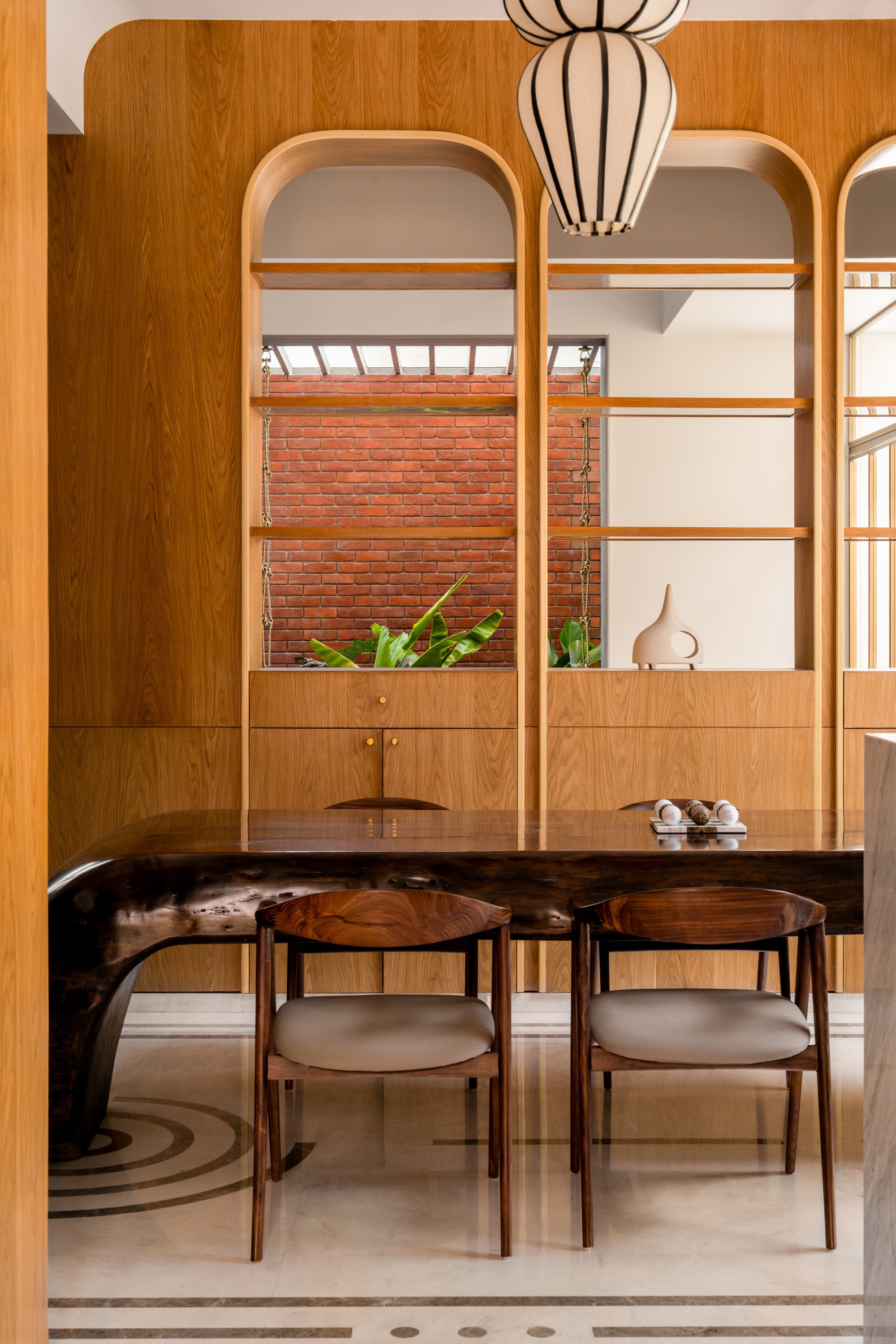 Dining area with rounded timber shelving framing a view to the brick courtyard and planted bed beyond