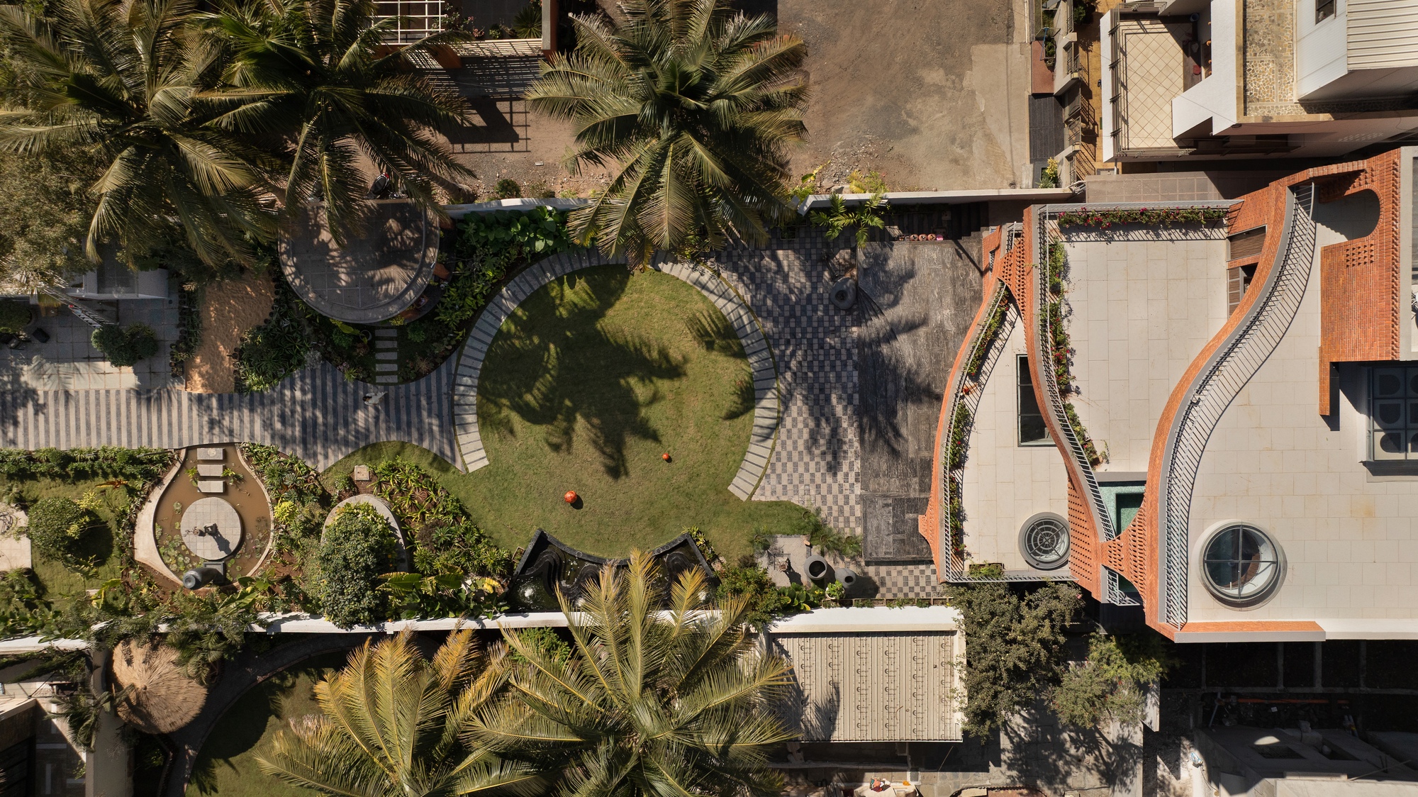 Aerial view of courtyard with paved paths, central lawn and palms casting shadows across adjacent buildings