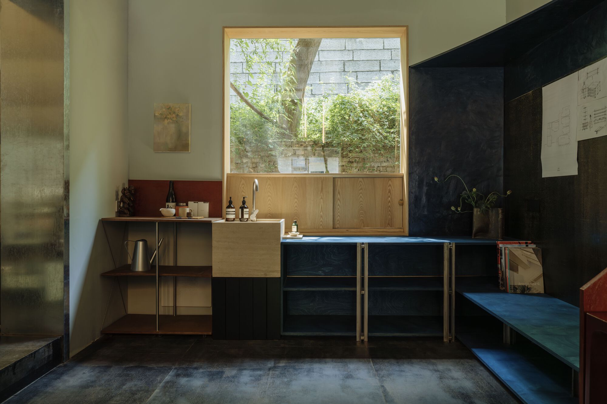 Kitchen counter and window overlooking courtyard with concrete block retaining wall and greenery