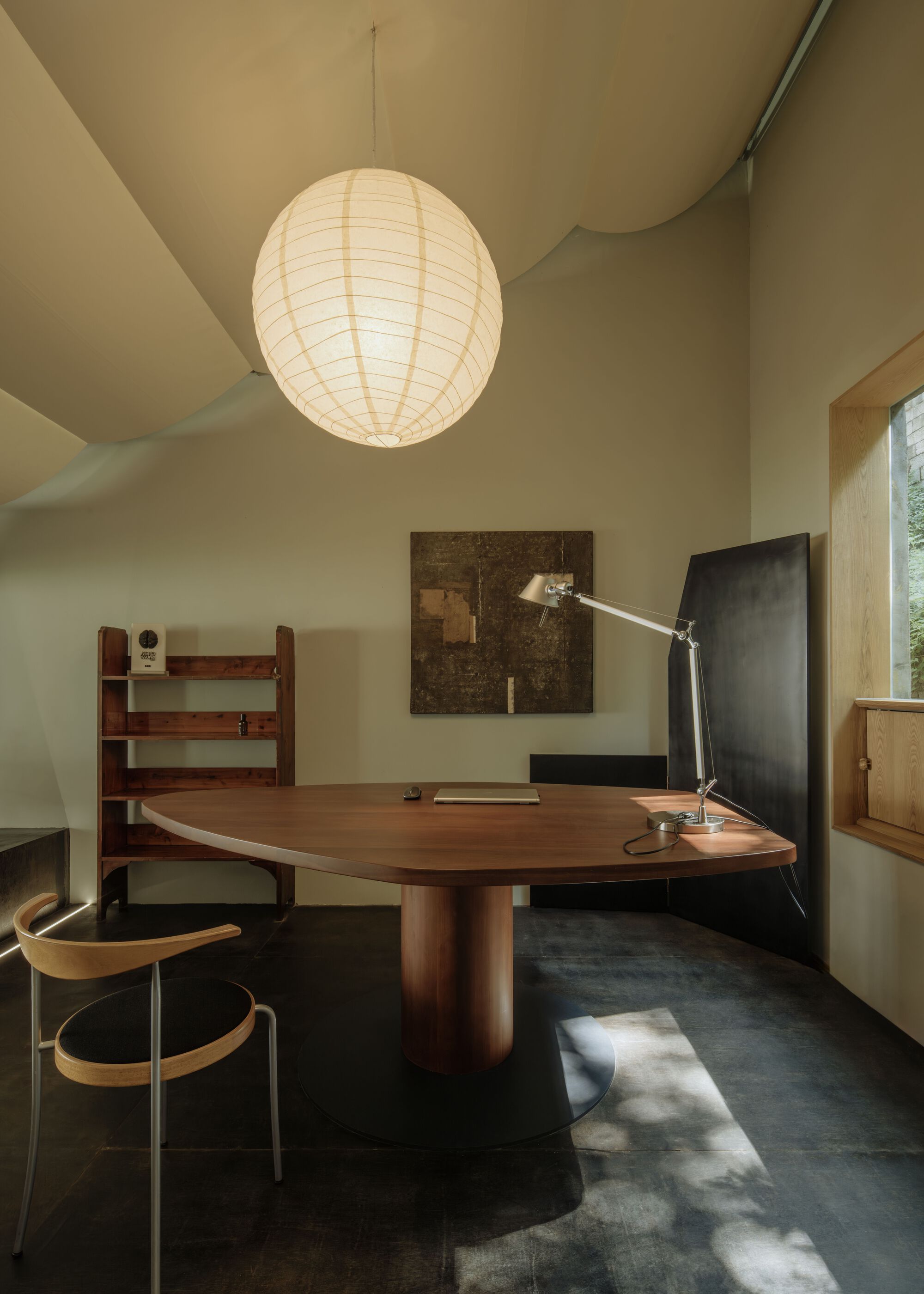 Workspace showing walnut desk with articulated lamp and paper globe pendant in afternoon light