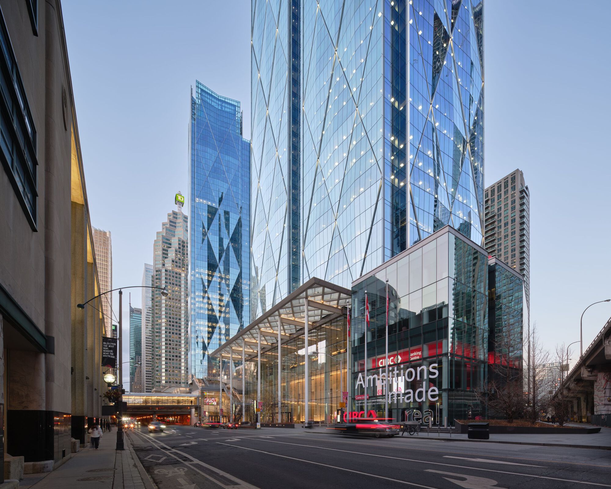 Street-level view showing the lattice canopy entrance and tower facades rising above bare winter trees
