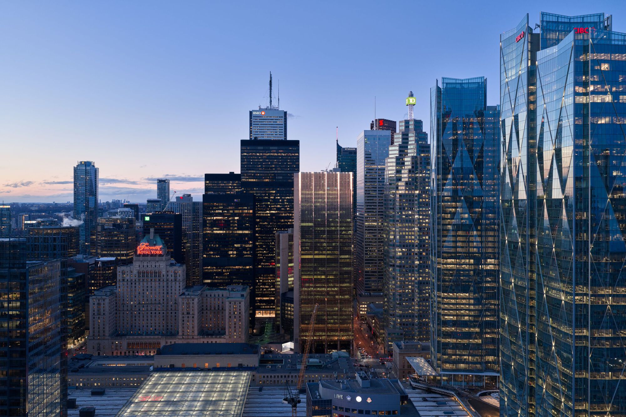 Downtown skyline view with illuminated glass towers and railway infrastructure below at sunset