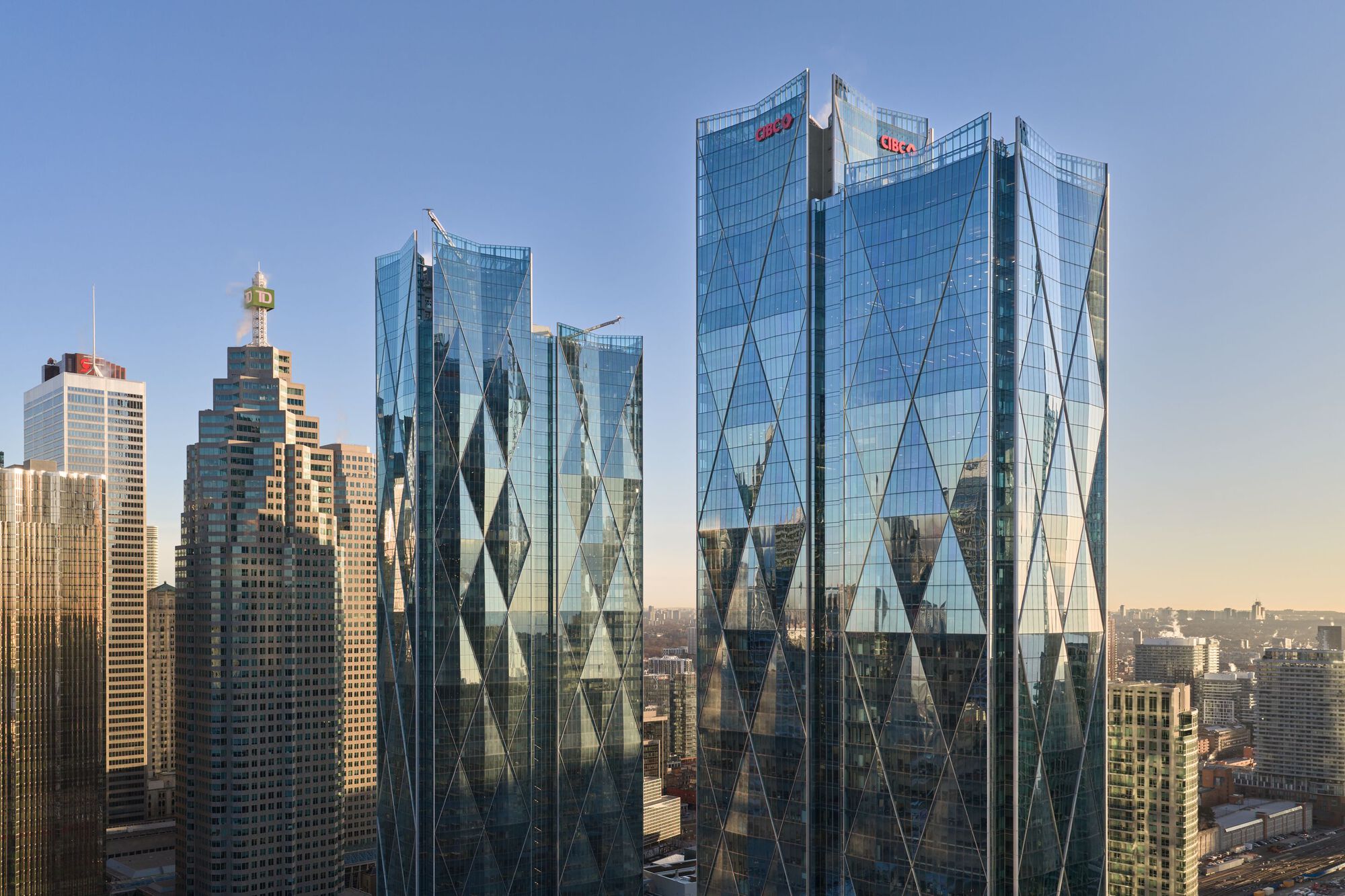 Twin glass towers with diagonal bracing pattern rising above the downtown skyline in afternoon light