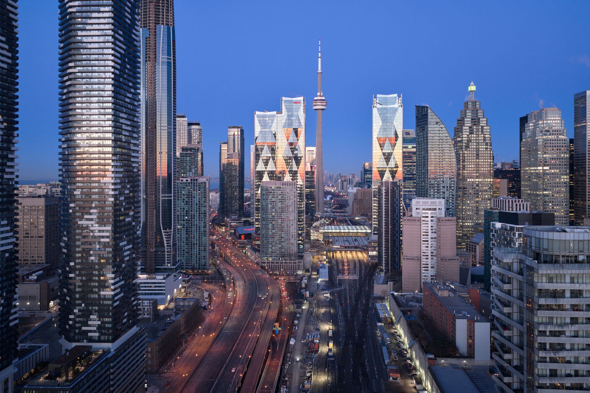 Wide cityscape showing the twin towers flanking a multi-lane highway with car light trails