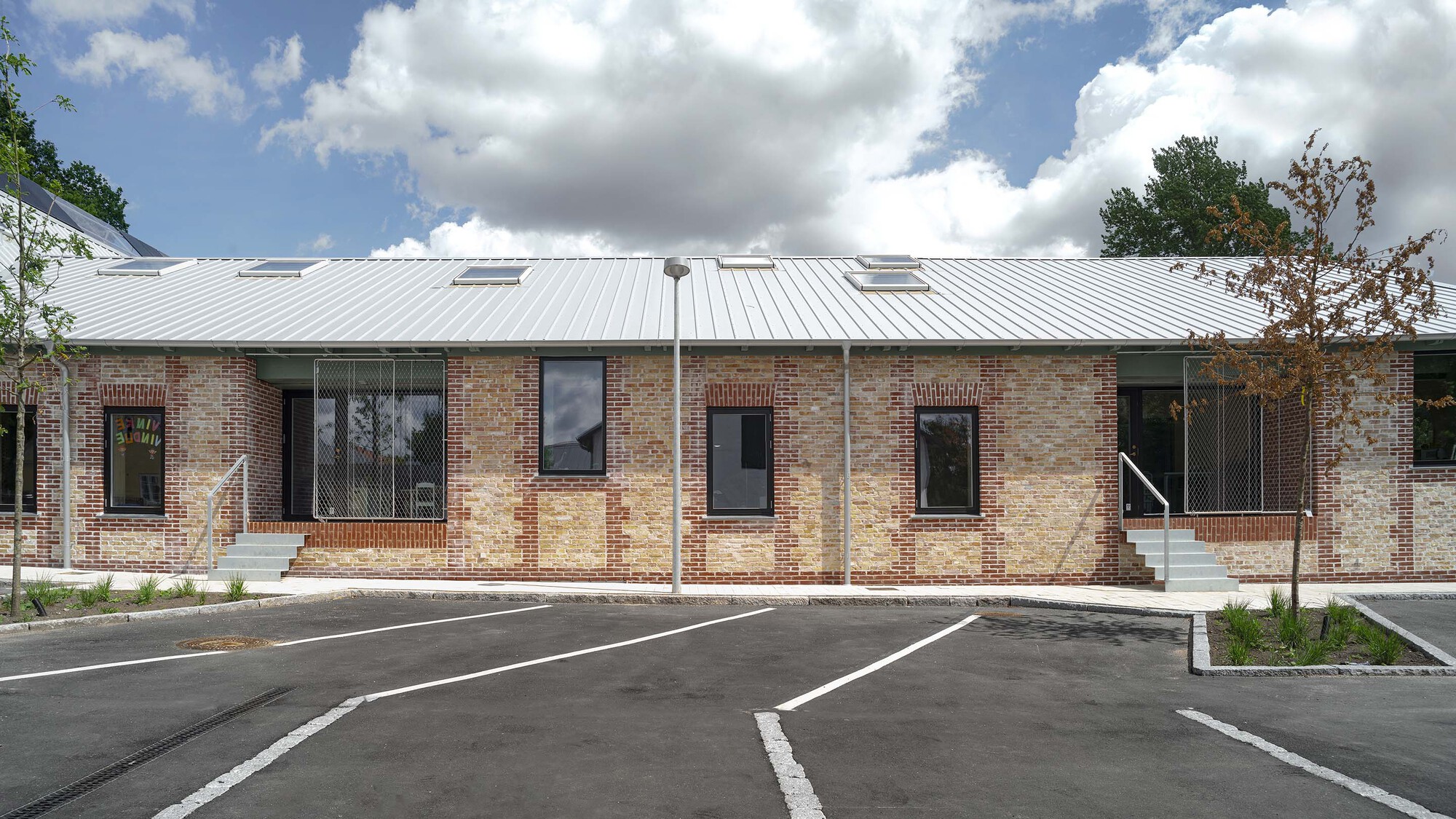 Street facade with mixed brick patterns and standing seam metal roof under a cloudy sky
