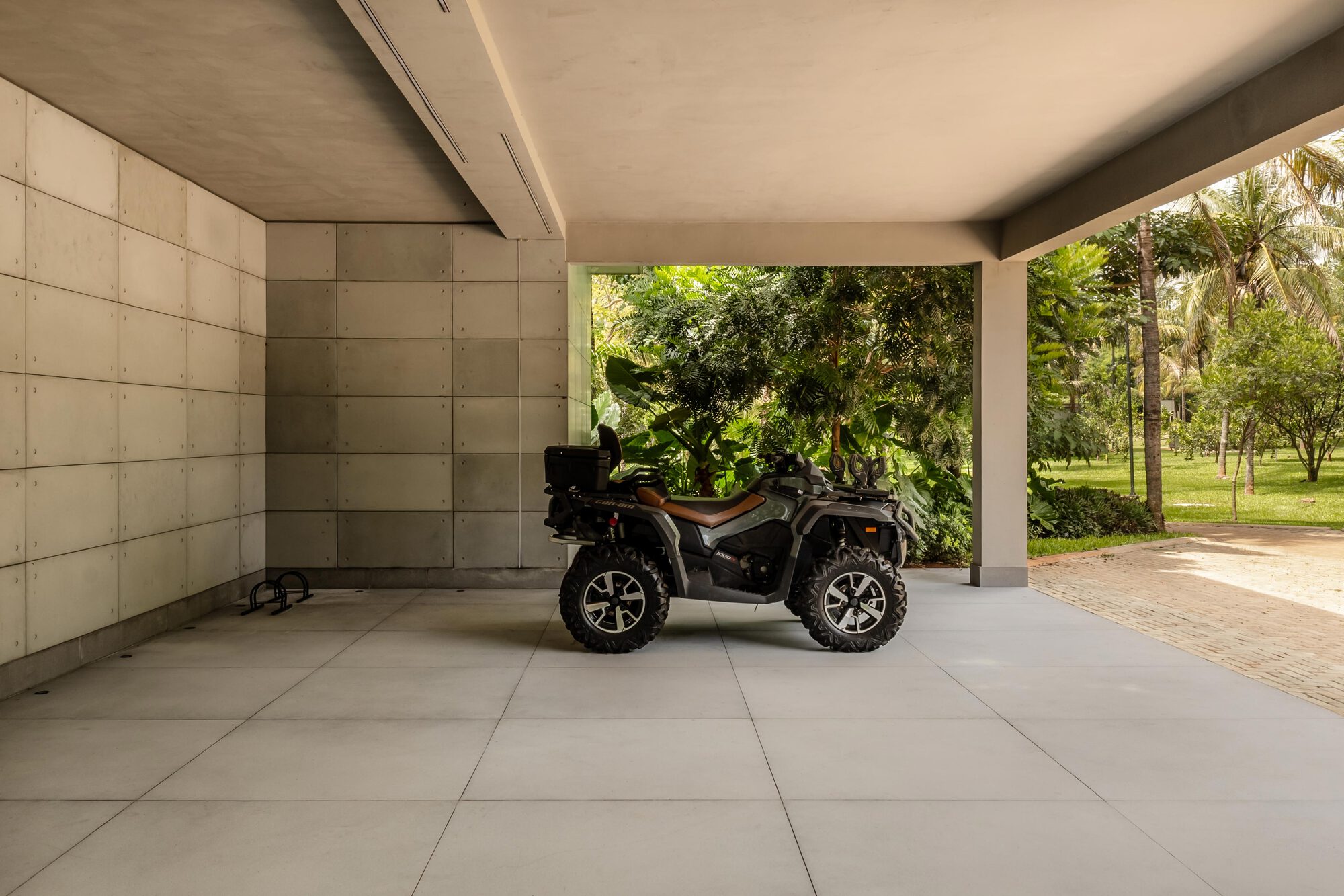 View from inside the carport framing the lush green landscape beyond the concrete floor