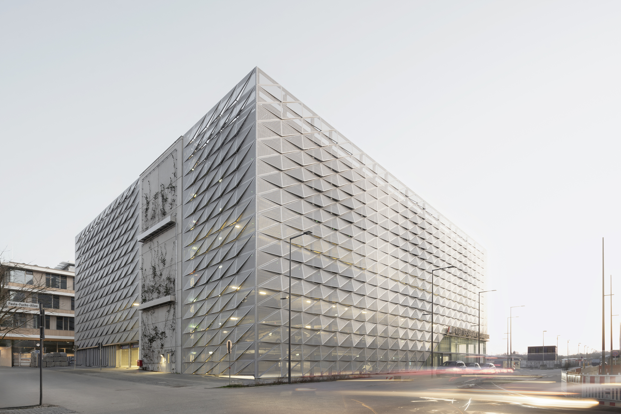 Corner view of the triangulated metal facade with perforated panels under an overcast sky
