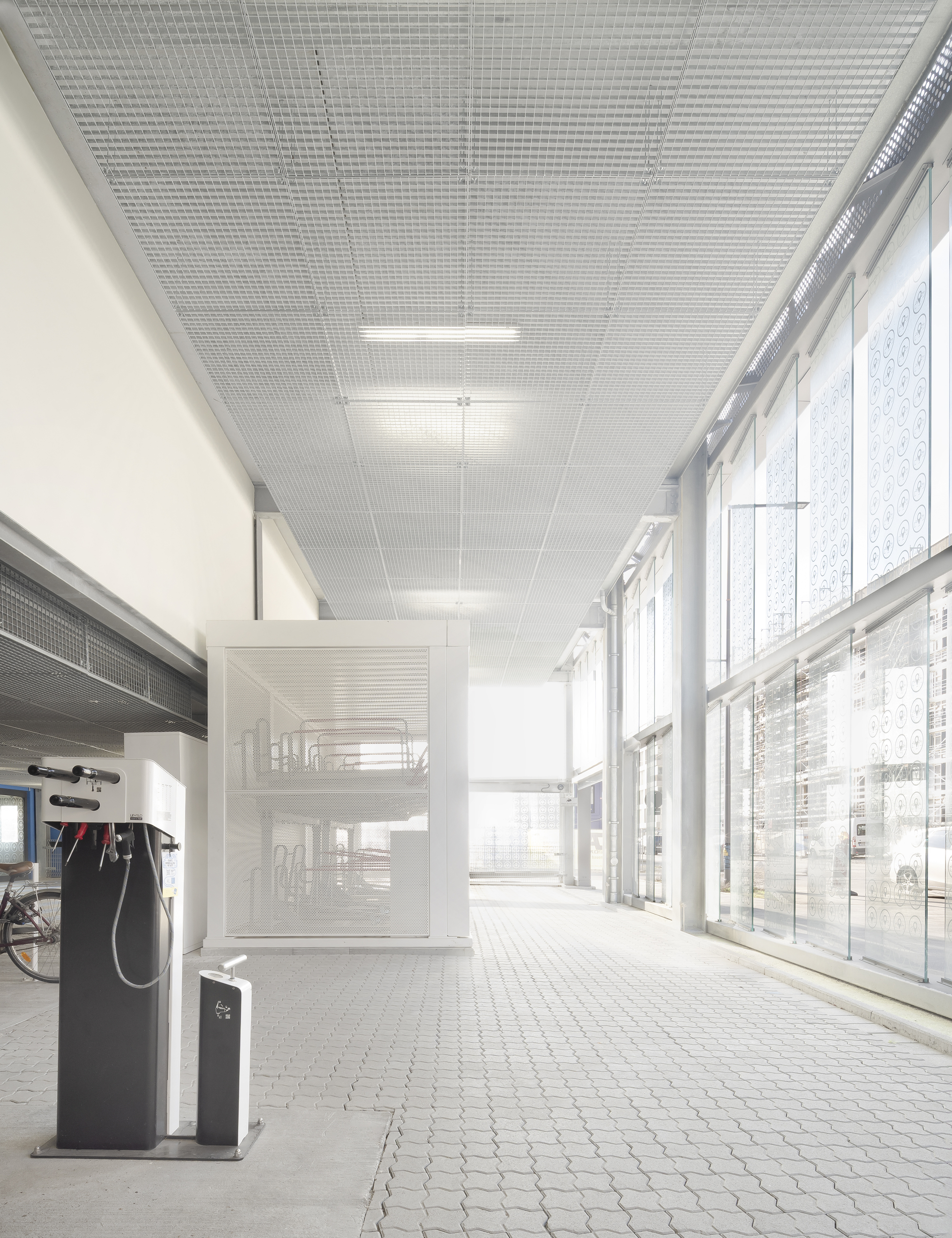 Interior ground floor corridor with perforated metal ceiling and full-height glazed curtain wall
