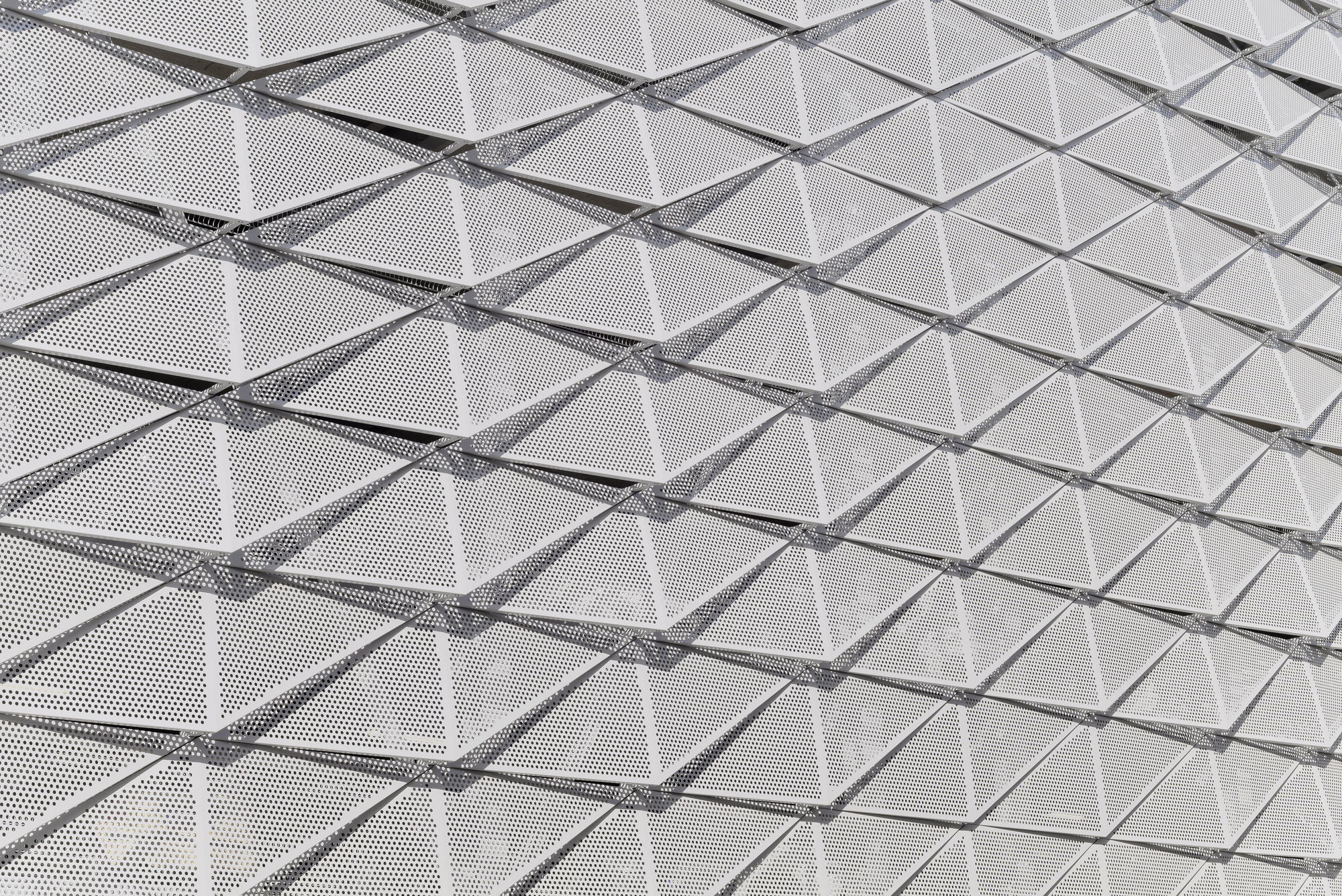 Close-up of perforated metal panels with triangulated structural members creating a geometric facade pattern