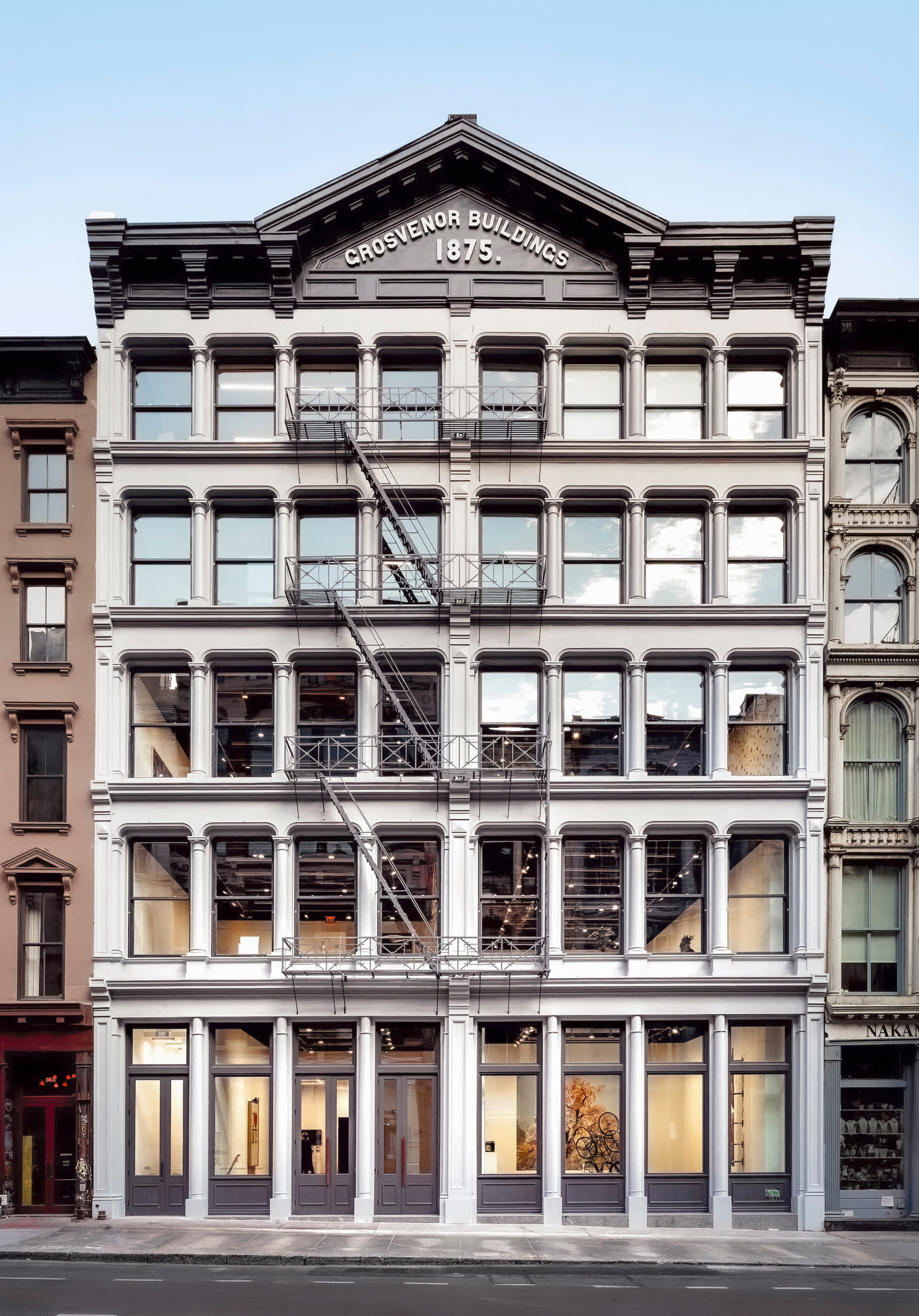 Five-story cast-iron facade with pediment and large glazed openings in late afternoon light