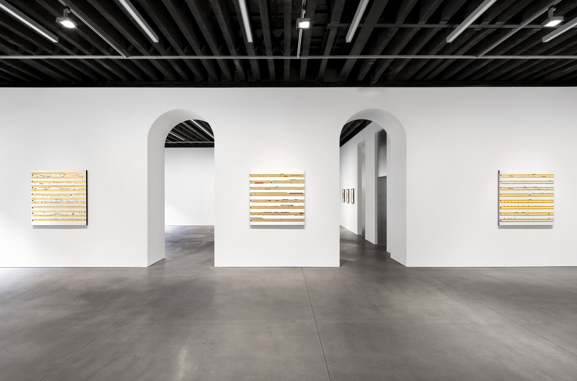 White partition wall with two arched openings beneath black painted joist ceiling