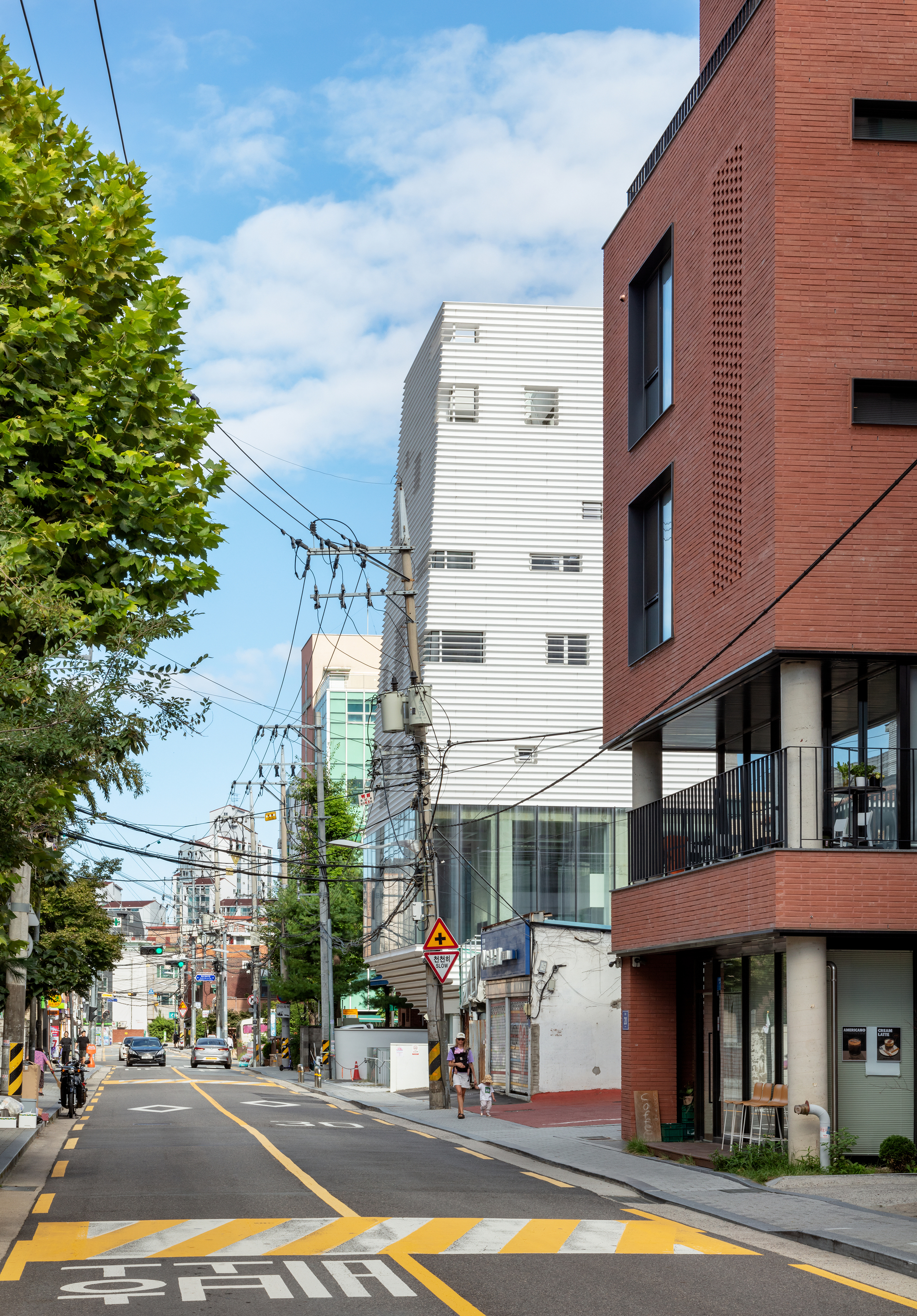 The white louvered tower rising behind street trees and adjacent brick buildings with overhead utility wires