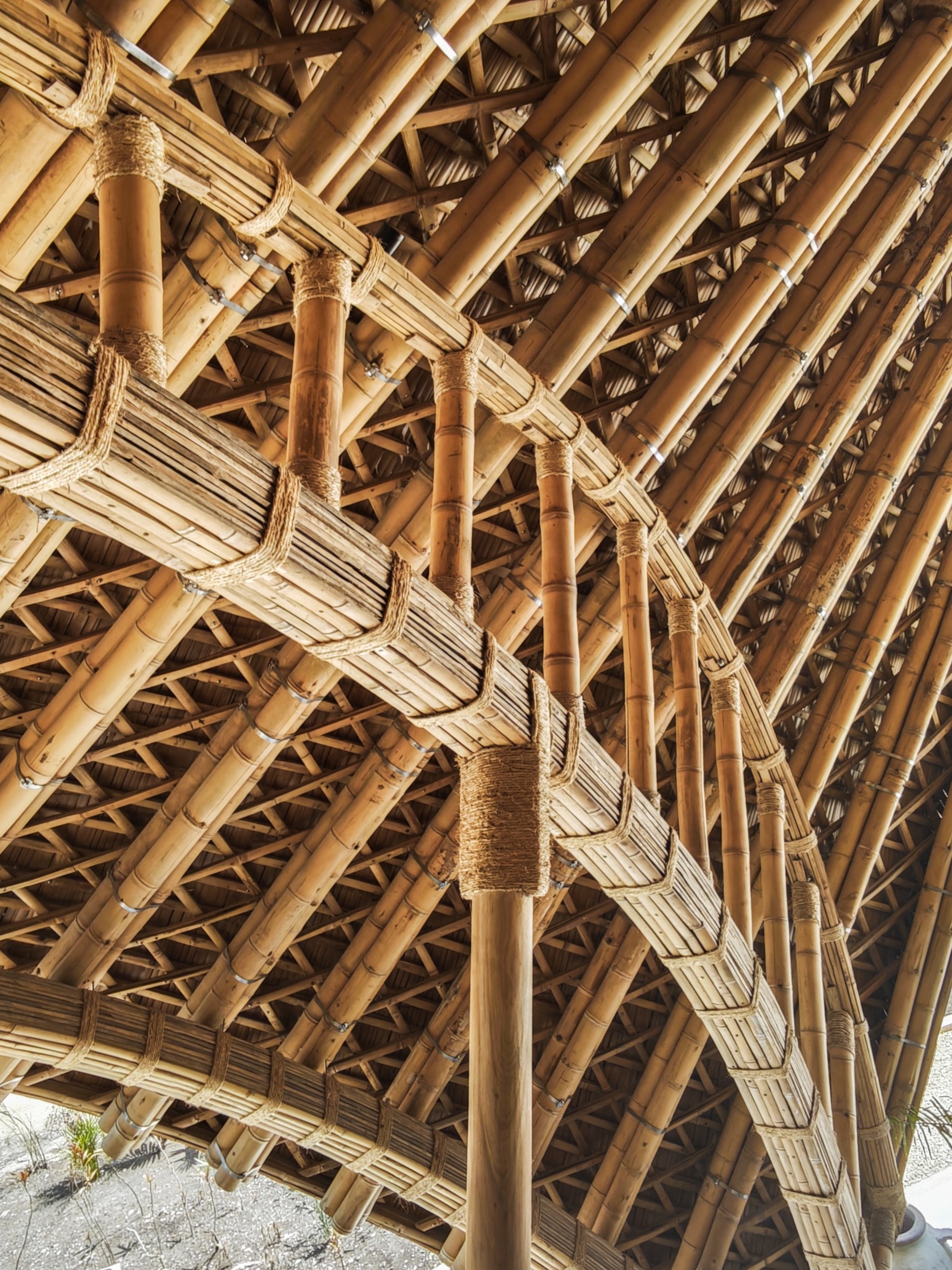 Close-up of the bundled bamboo columns and diagonal lattice members with rope lashing at the roof structure