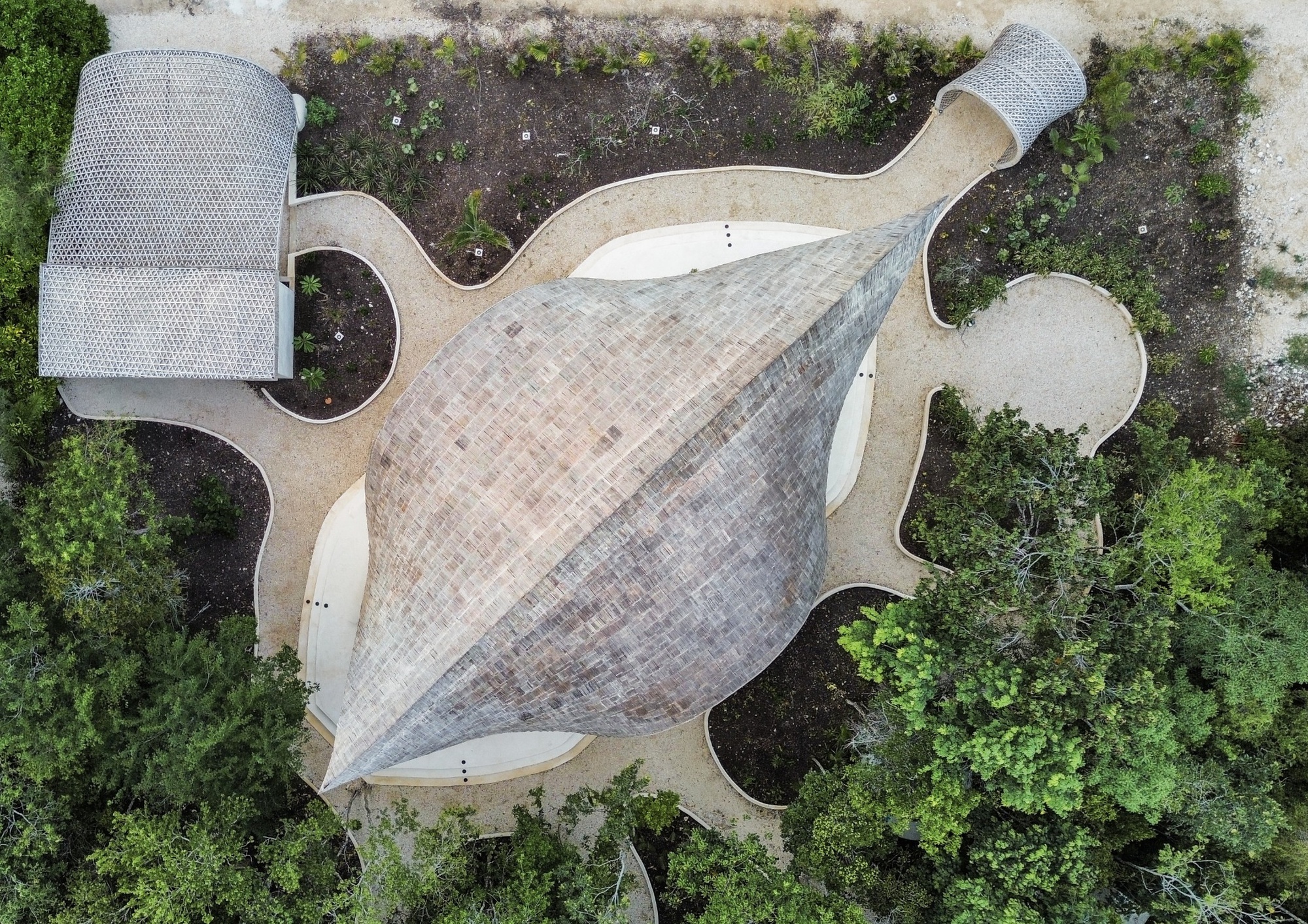 Aerial view of the lobed shingled roof surrounded by planted beds and vegetation