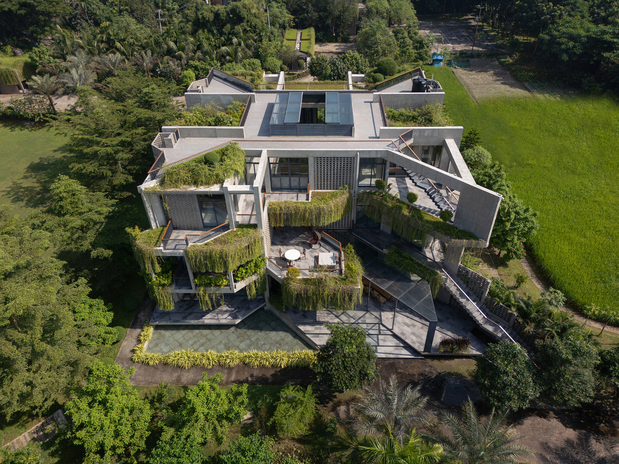 Aerial view of the multi-level residence with planted terraces and green roofs surrounded by trees and lawn