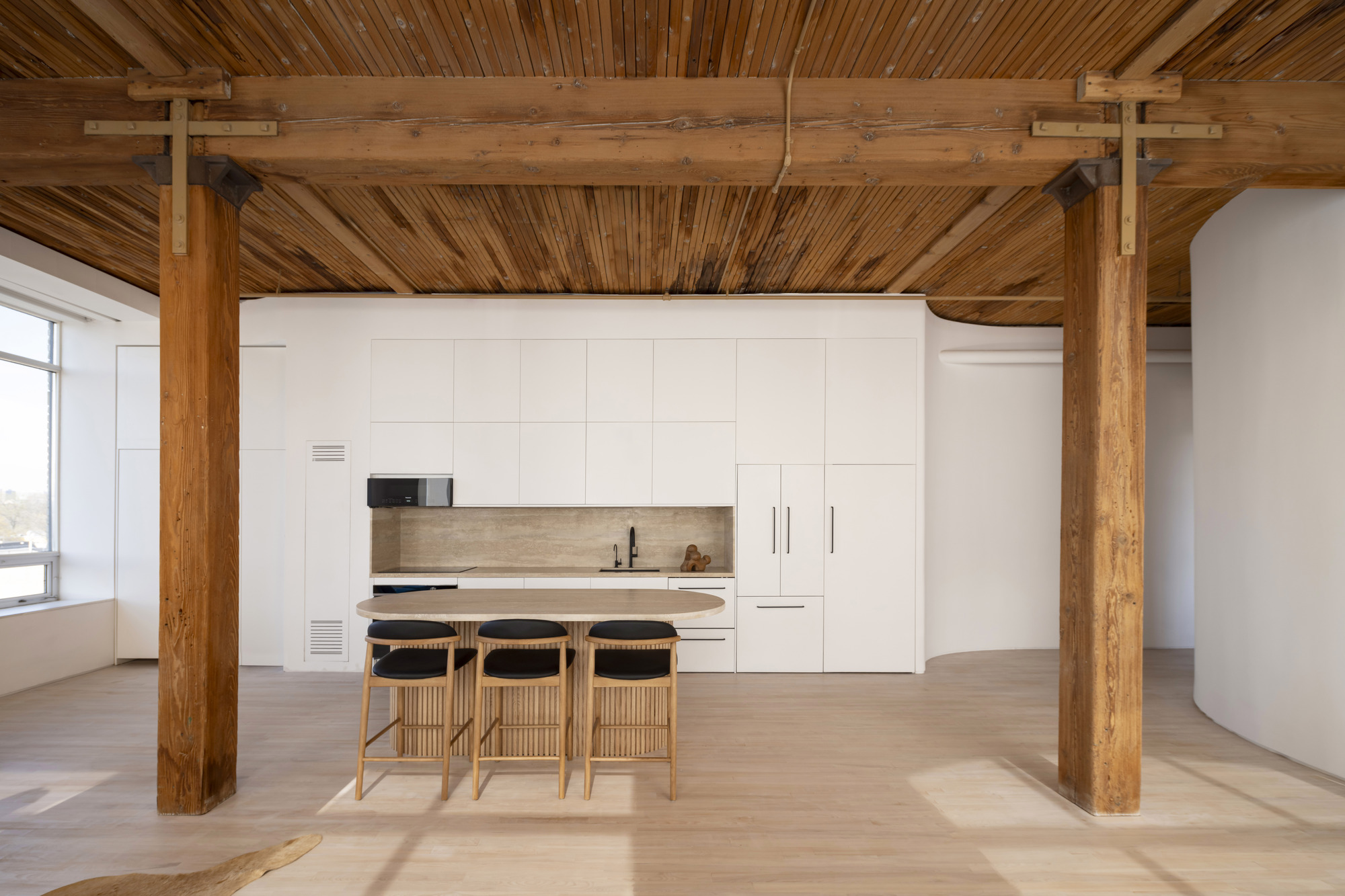 Kitchen area framed by exposed timber beams and columns with slatted wood ceiling in afternoon light