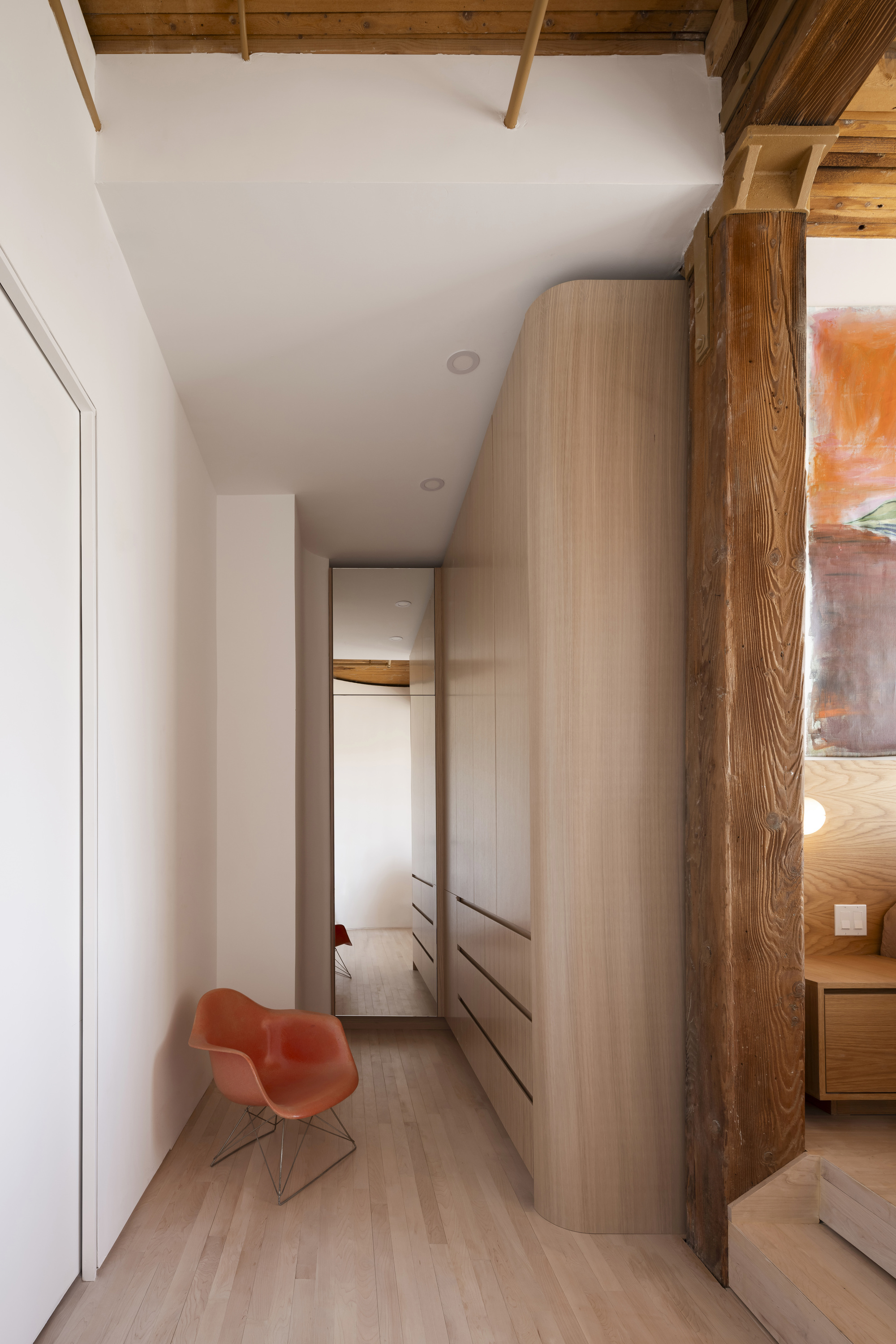 Narrow corridor with exposed timber beams above and curved built-in cabinetry along one wall