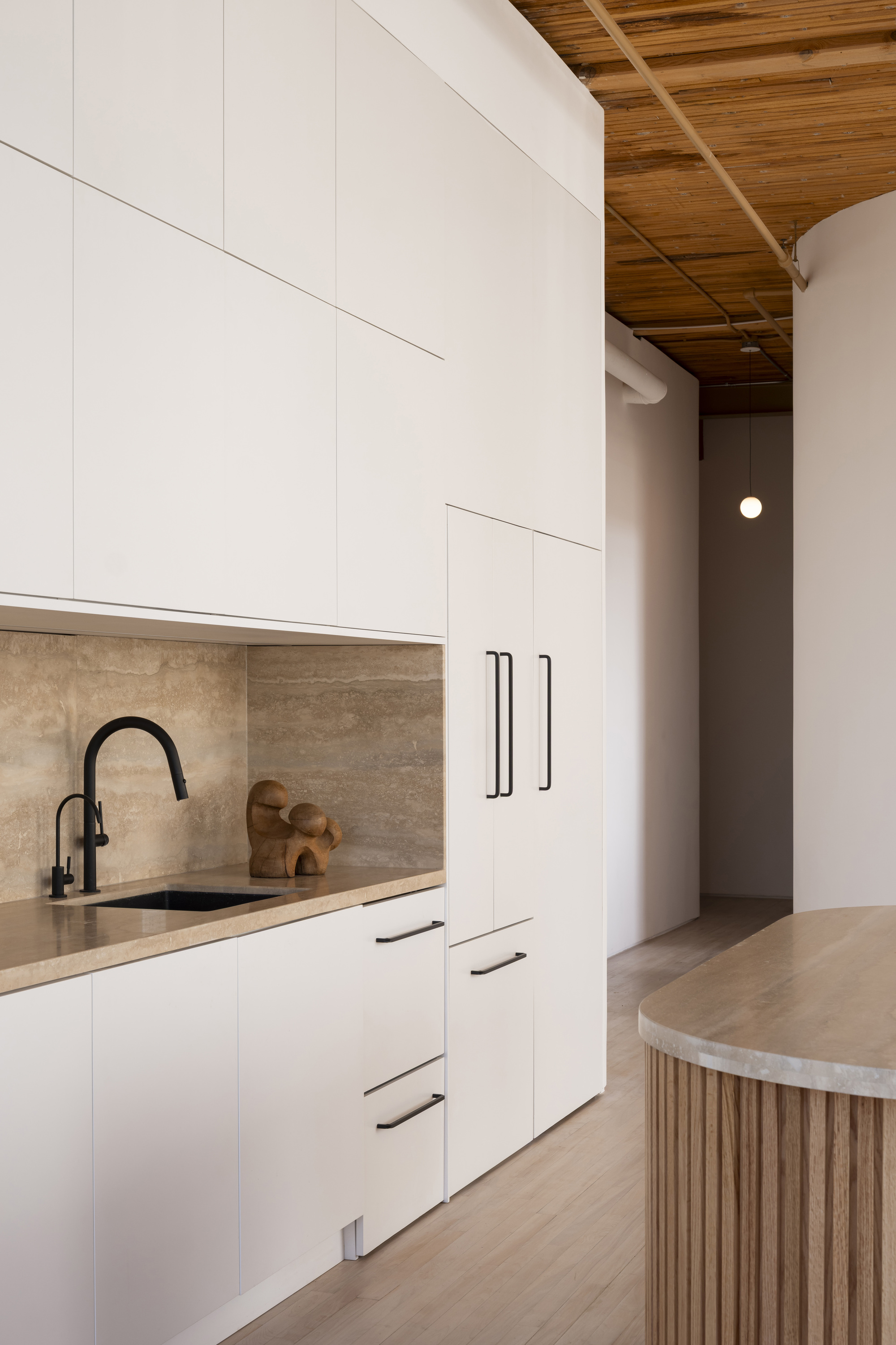 Galley kitchen with white cabinets, travertine backsplash and timber coffered ceiling above