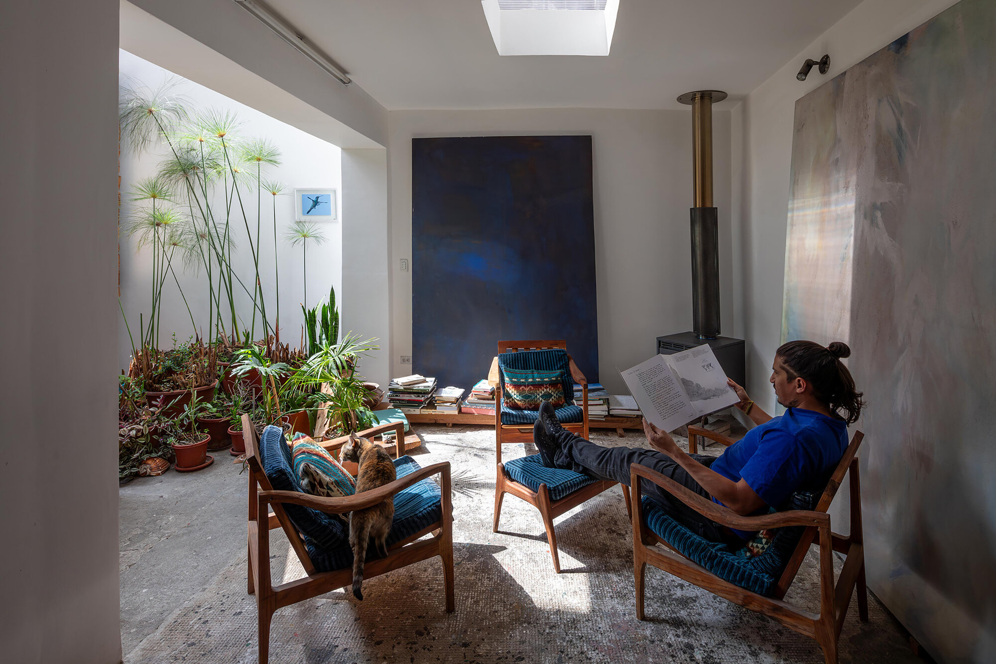Reading area with metal woodstove beneath skylight and planted courtyard beyond