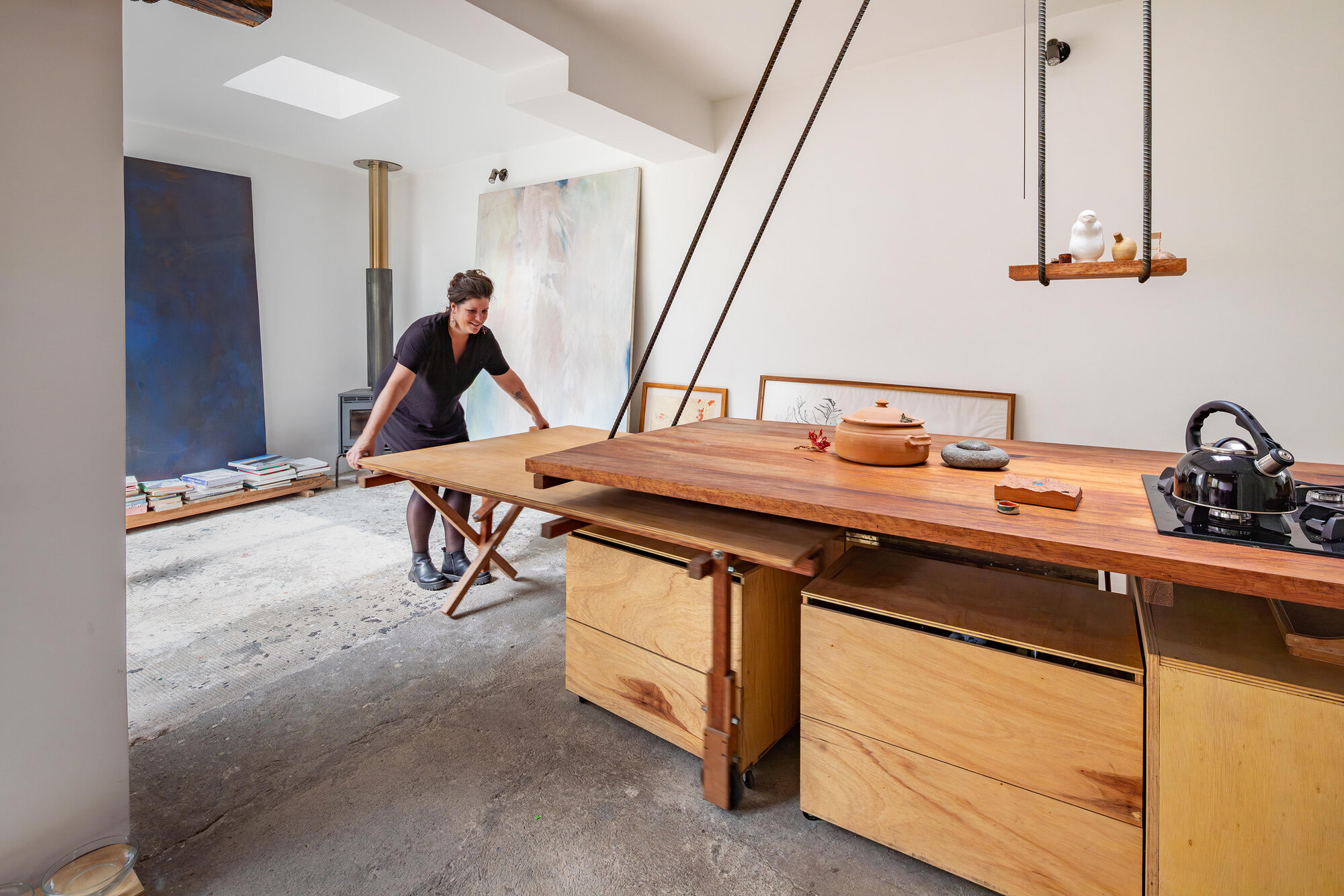 Workspace with adjustable timber table and exposed copper pipe lighting suspended from ceiling