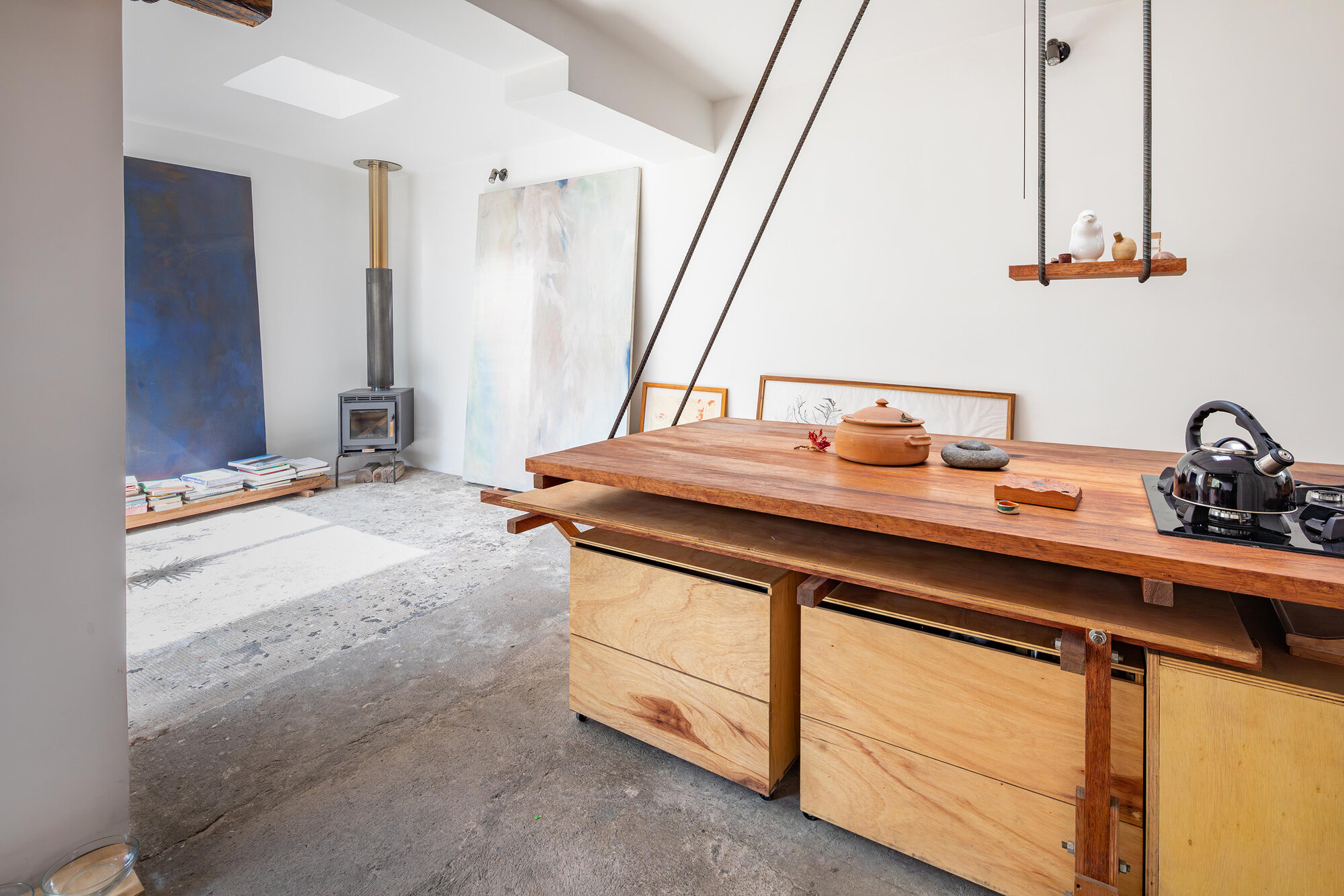 Open-plan interior showing polished concrete floor, skylight, and timber counter with mobile storage modules beneath
