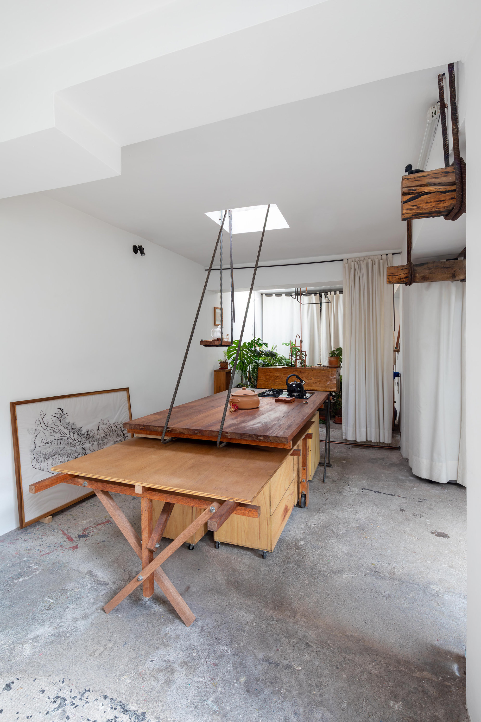 View toward curtained partition showing suspended timber shelf system and adjustable work counter on concrete floor