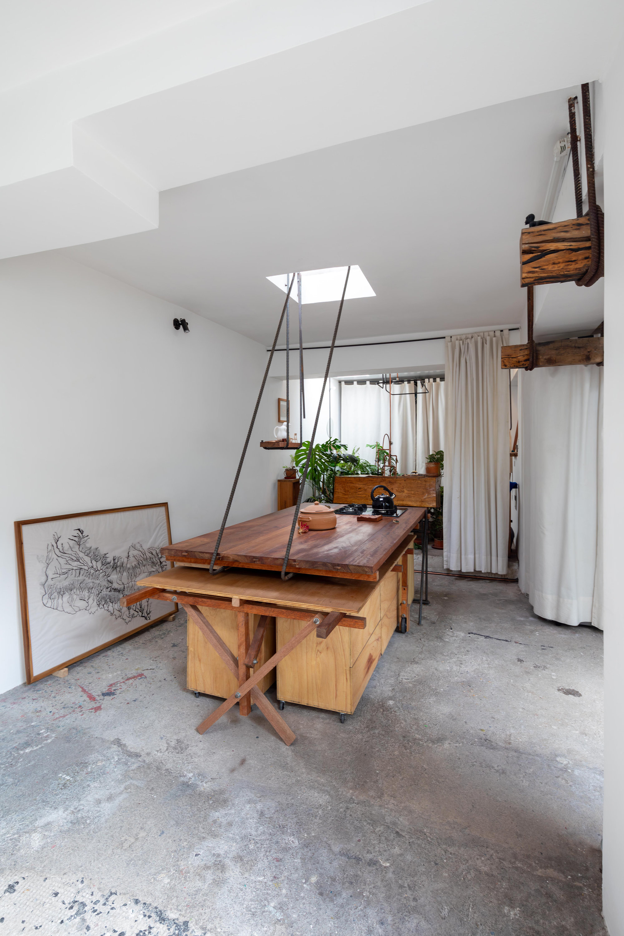 Workspace with timber trestle table and suspended skylight under white vaulted ceiling