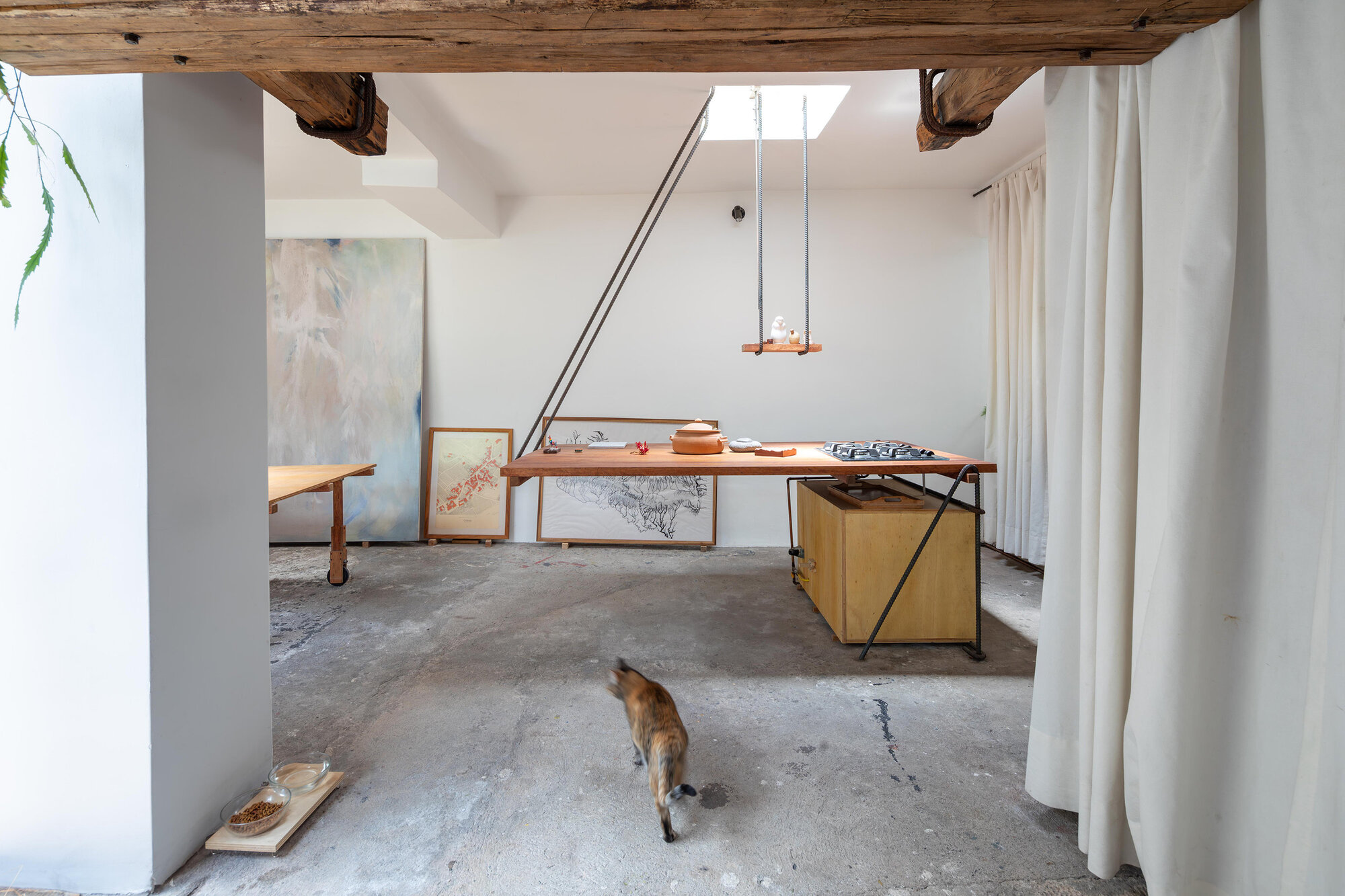 Studio interior with polished concrete floor and timber worktable as a dog walks through