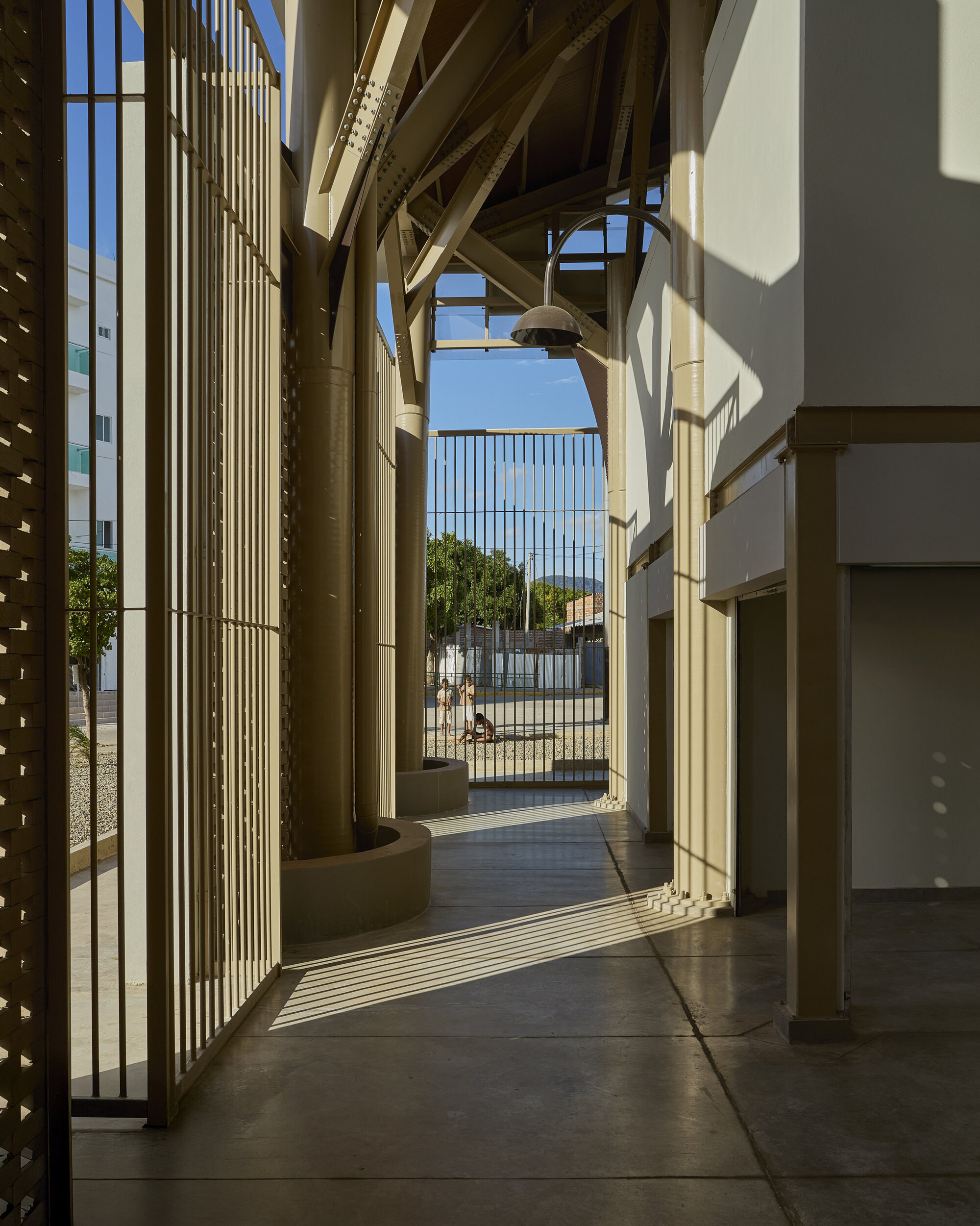 Covered walkway with timber columns and vertical slat screens casting shadows on polished concrete floors