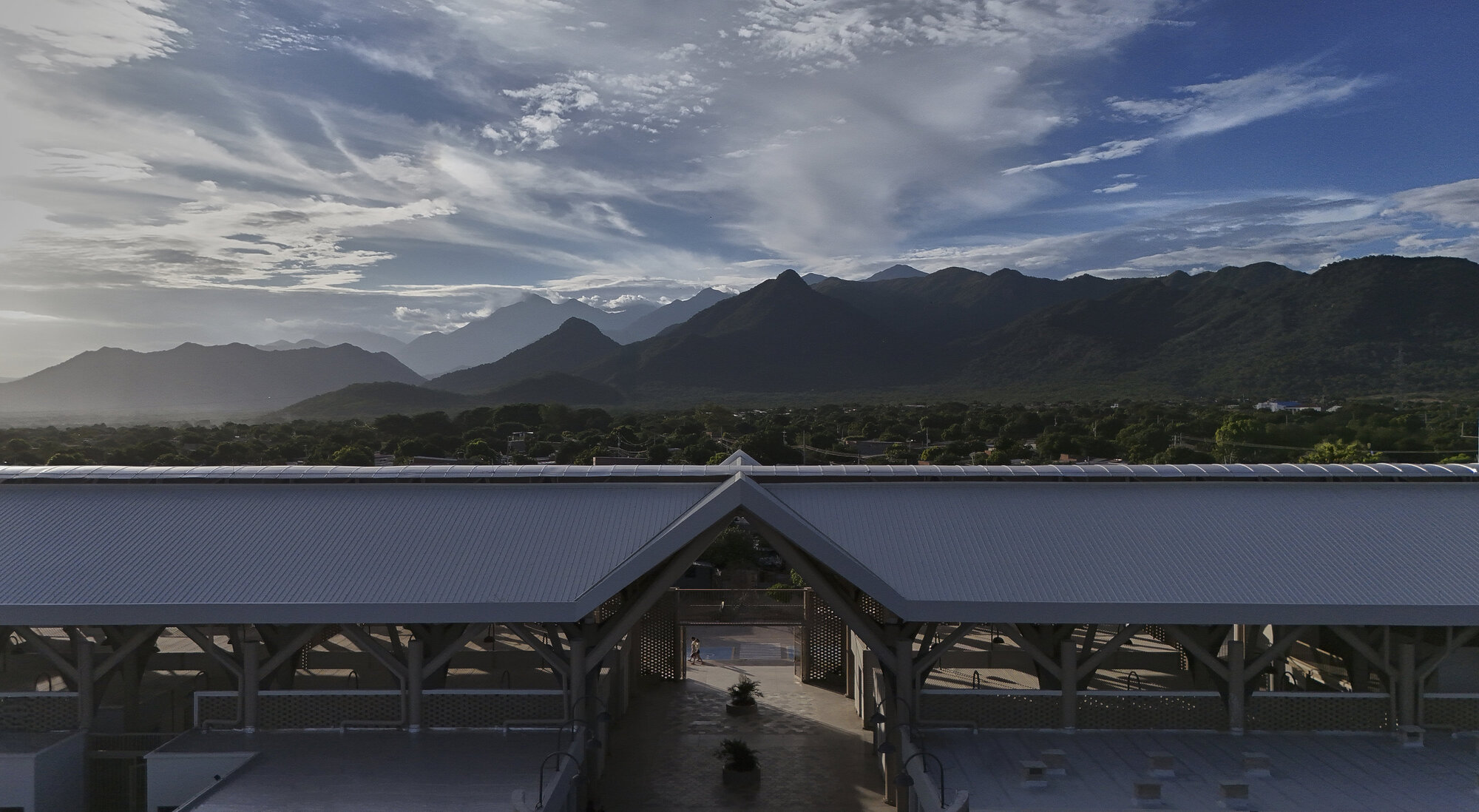 Aerial view of the gabled metal roof with exposed timber structure against a mountain range
