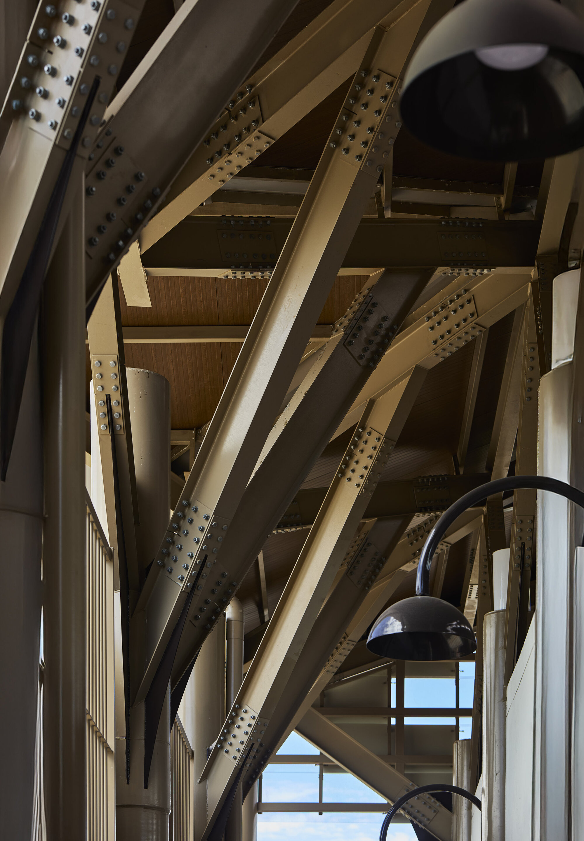Exposed timber truss system with bolted steel plates and pendant light fixtures