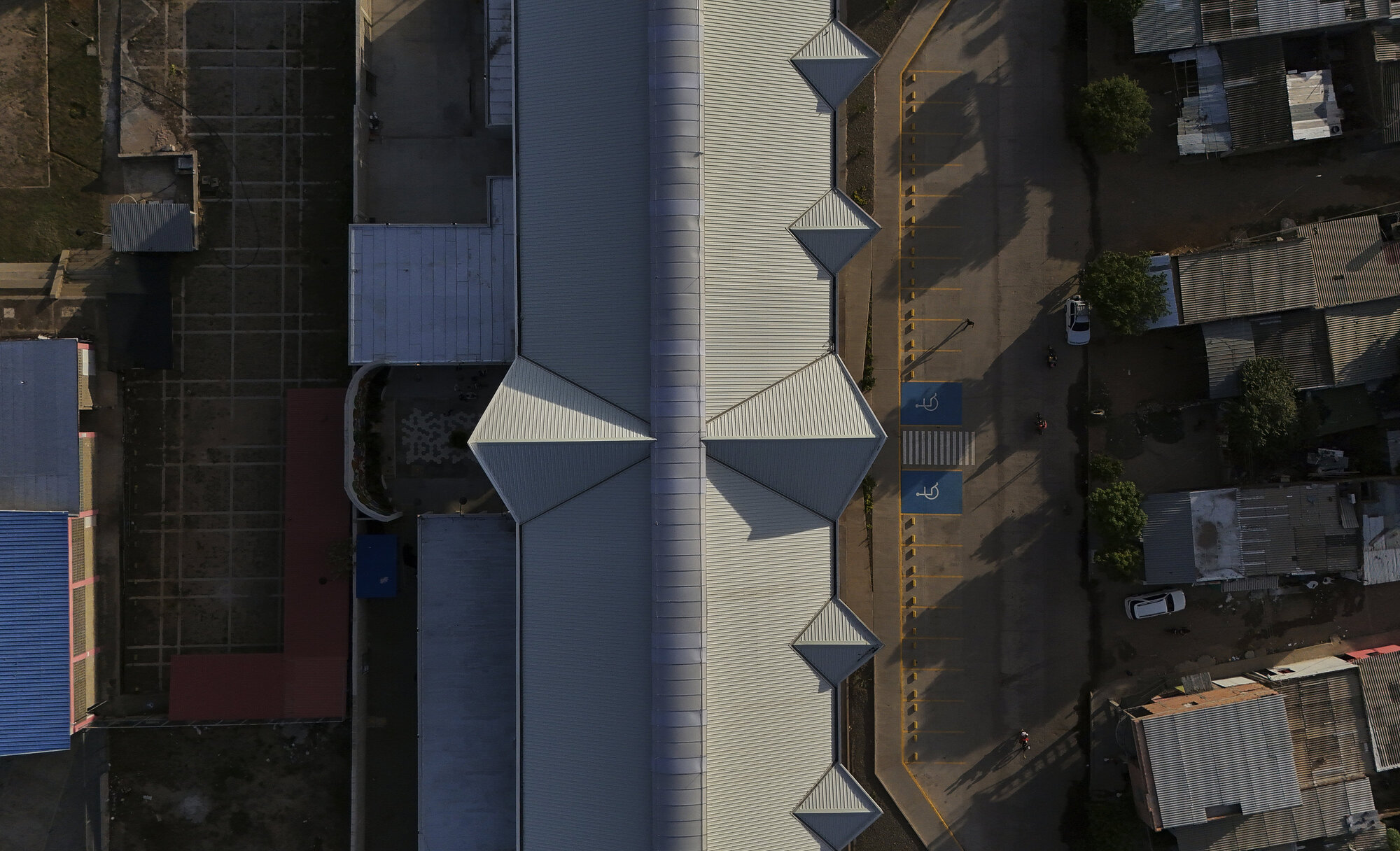 Aerial view of the corrugated metal roof with five triangular skylights and surrounding urban fabric