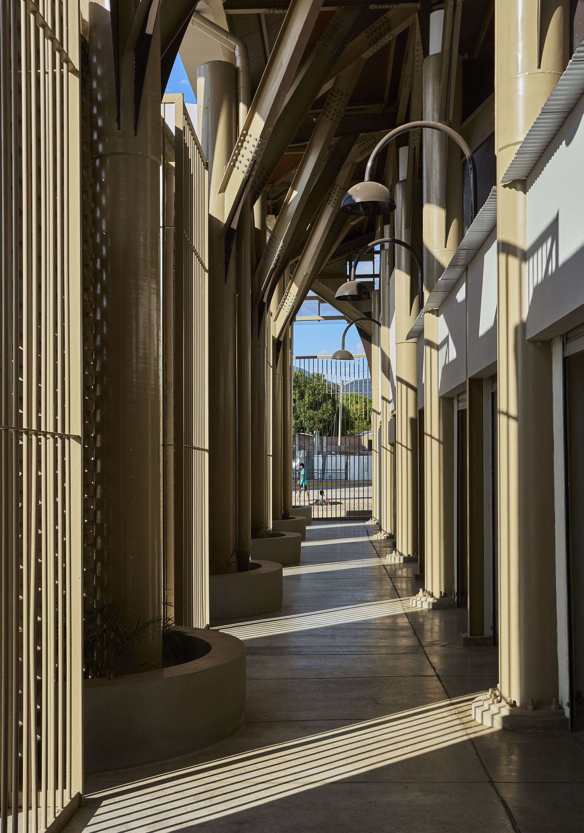 Colonnade with cylindrical columns and diagonal timber bracing casting shadows in afternoon light