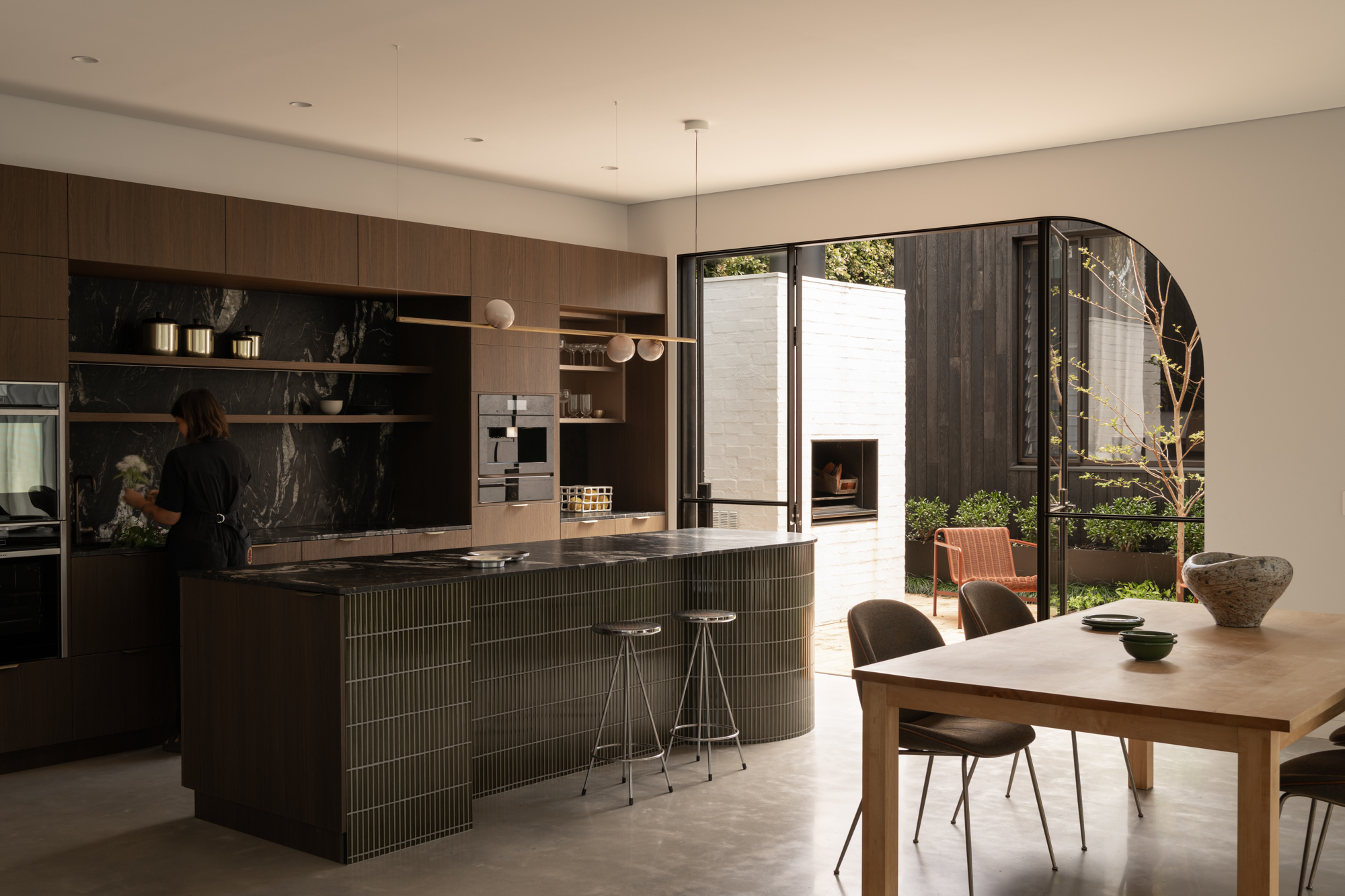 Kitchen and dining area with fluted island and arched opening to courtyard beyond