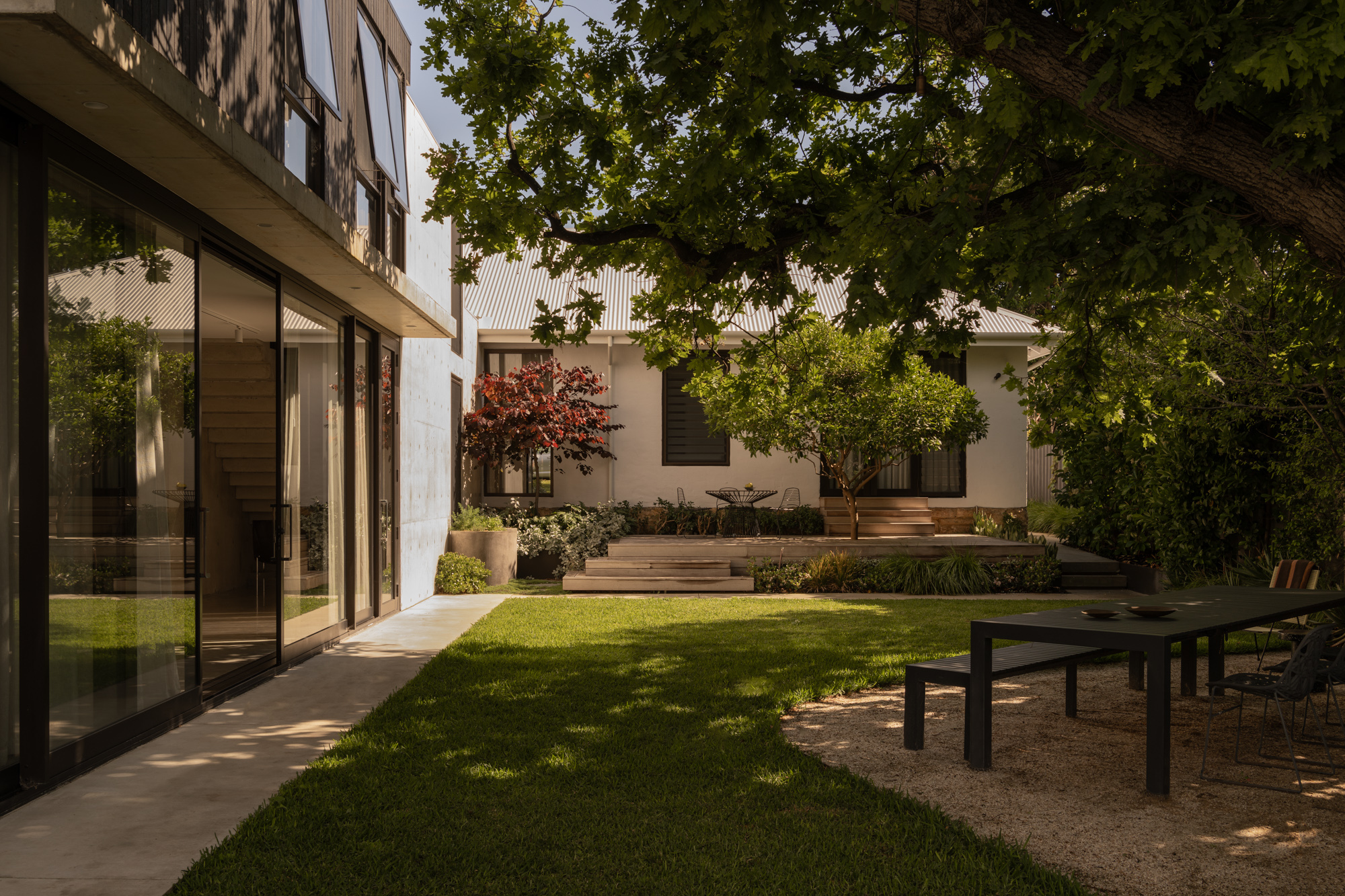 Garden view showing lawn, timber decking levels, and shade from an overhanging tree