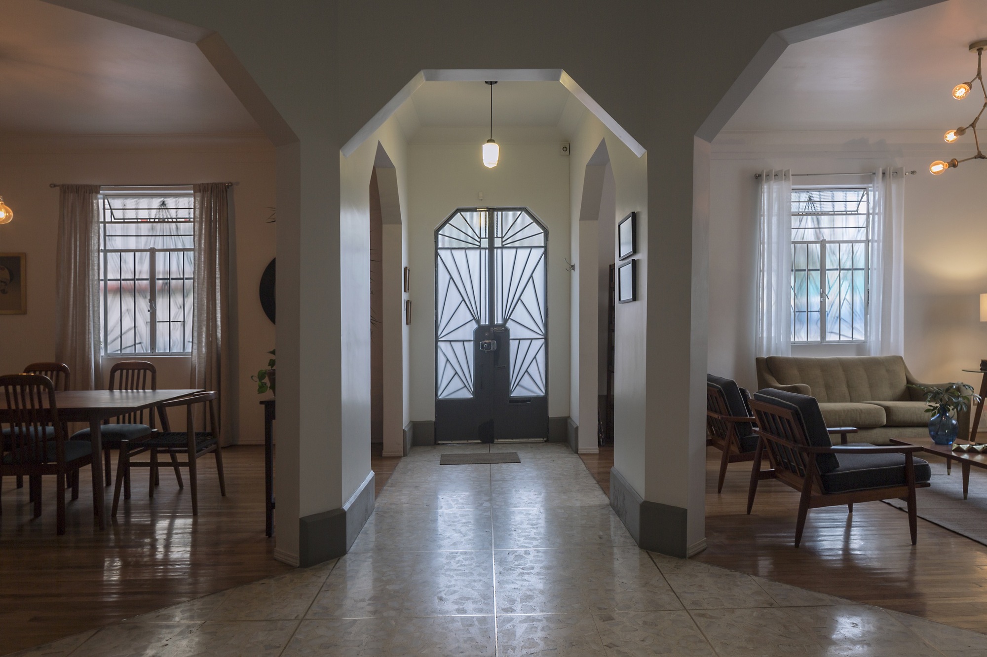 Entry hall with octagonal arches framing a geometric glazed door, terrazzo floor and dining and sitting rooms to either side