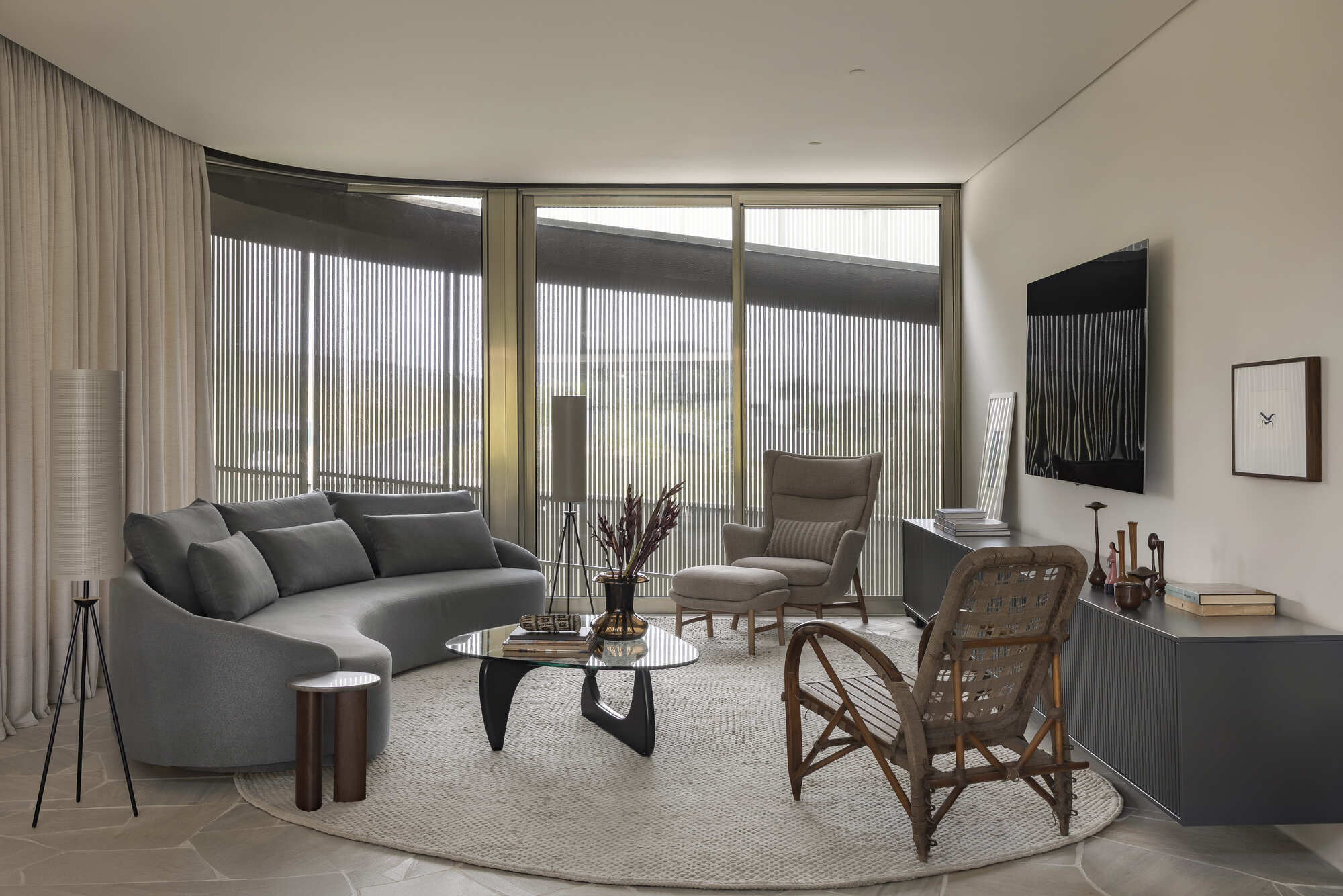 Living room with curved sofa and floor-to-ceiling windows framed by vertical metal screens