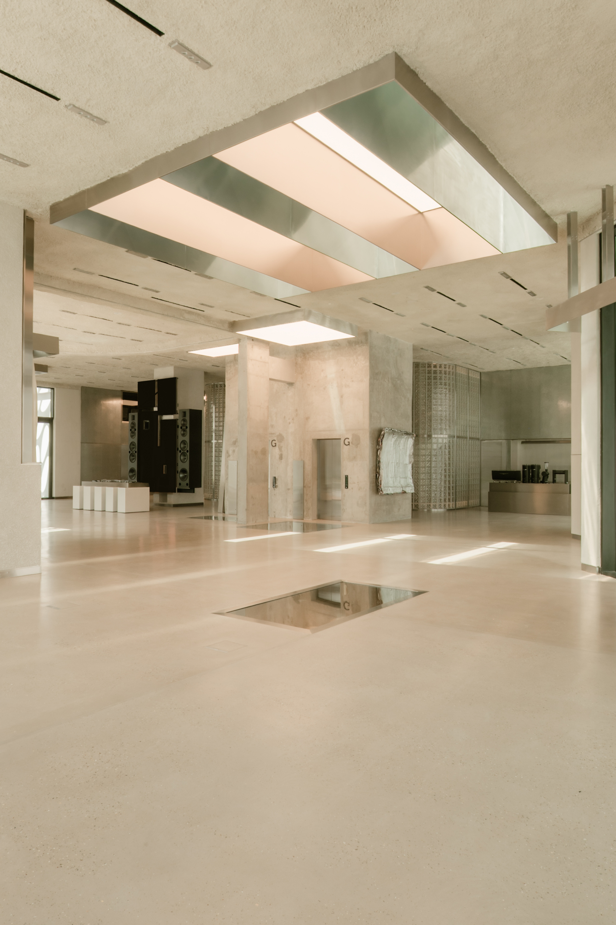 Main hall with suspended glass skylight, concrete columns and reflective floor insert below