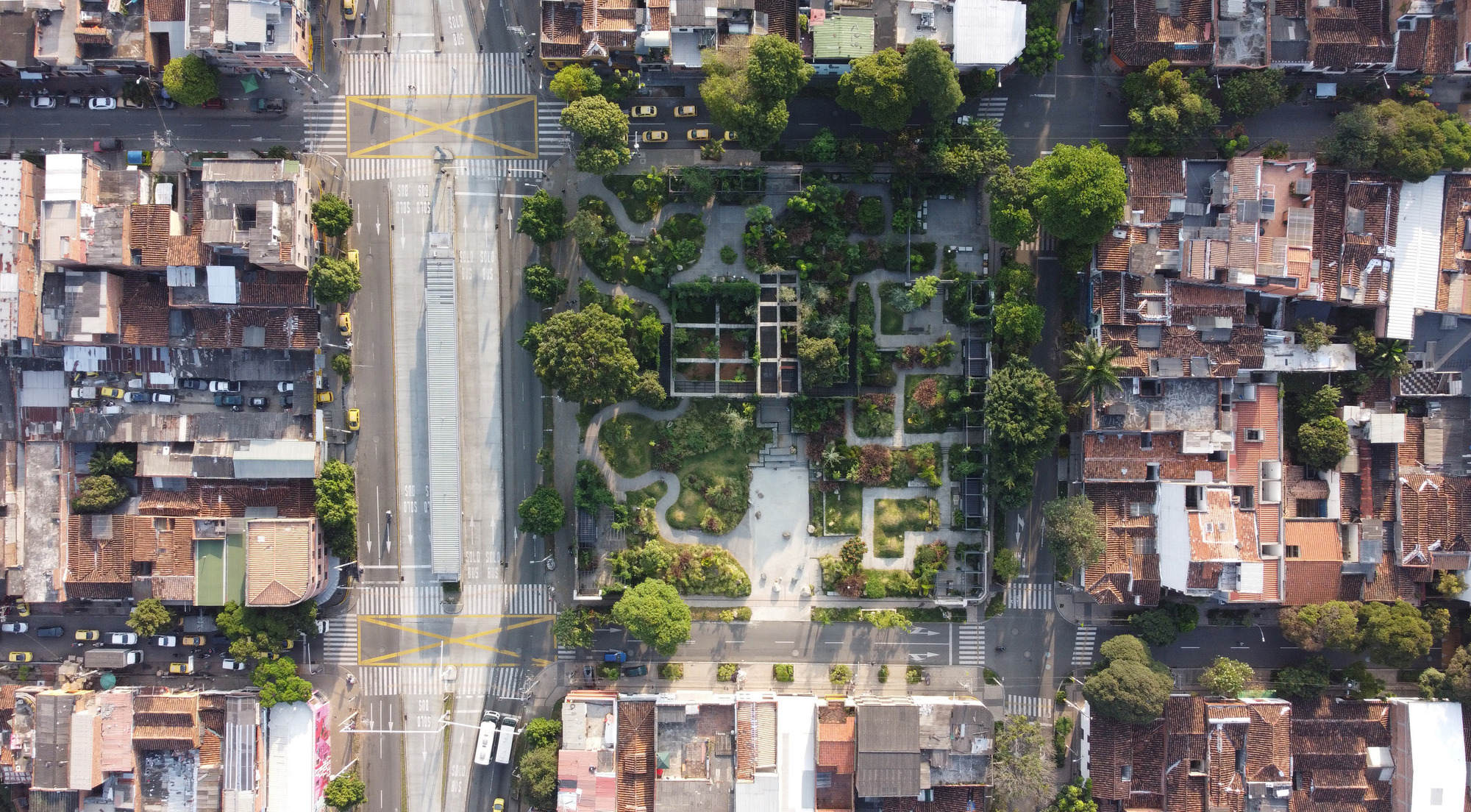 Drone view of terraced park inserted between dense urban blocks and a wide avenue