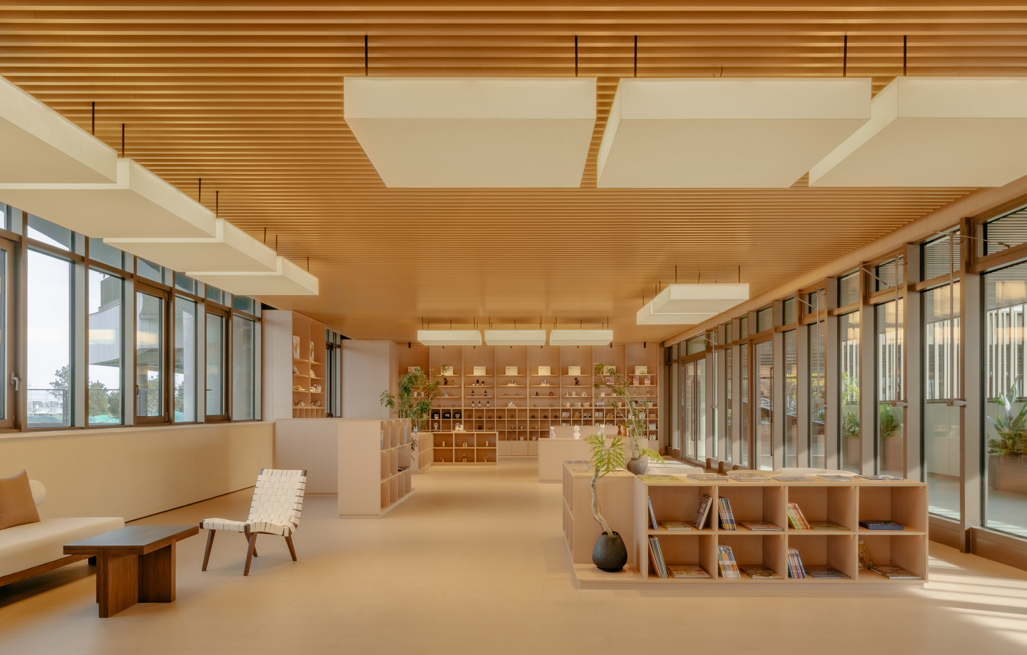 Full view of reception hall showing timber ceiling baffles and flanking glazed courtyards with low seating
