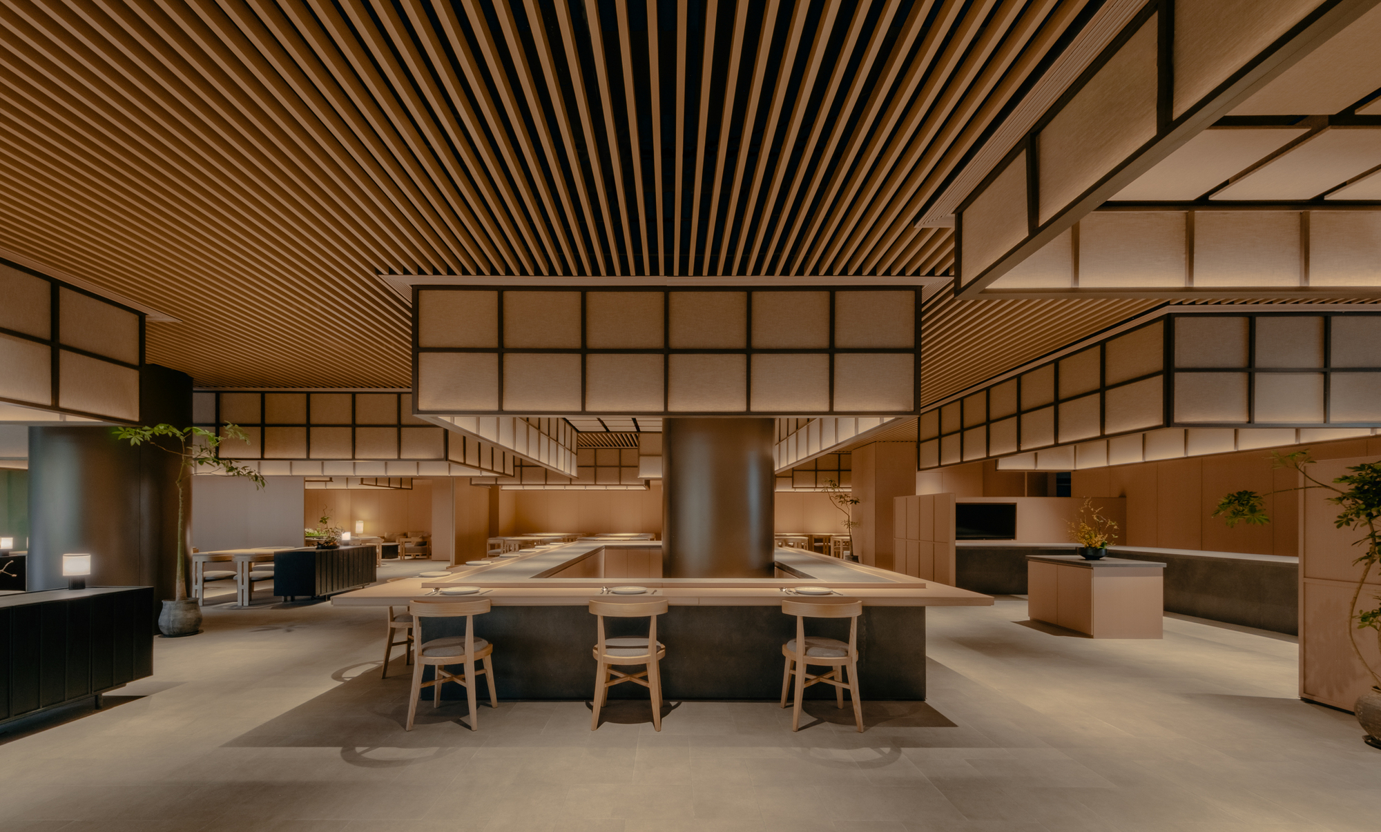 Double-height dining space with translucent gridded screens and a central cylindrical metal column in evening light