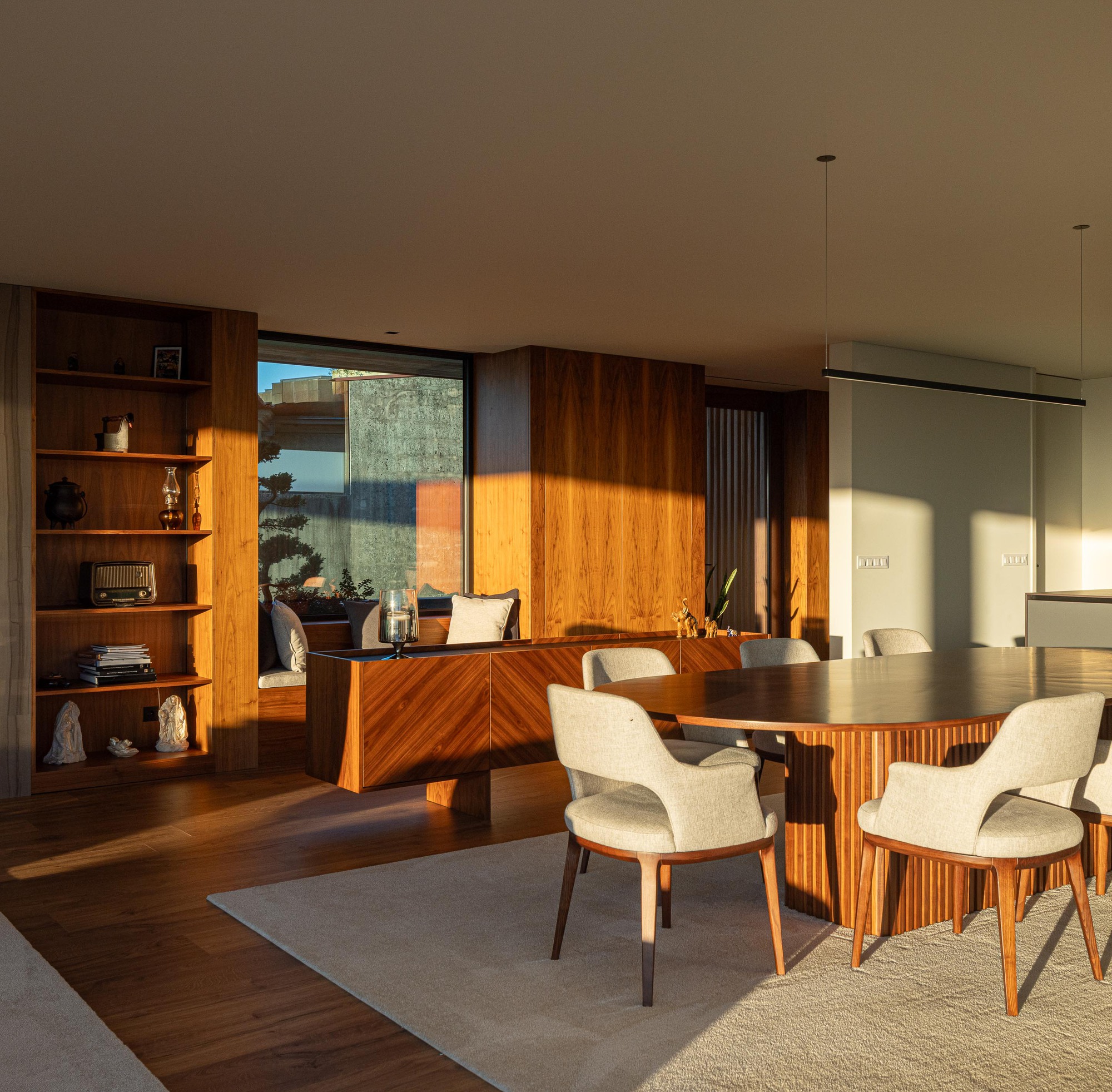 Dining room with timber paneling and built-in shelving bathed in afternoon sunlight from a corner window