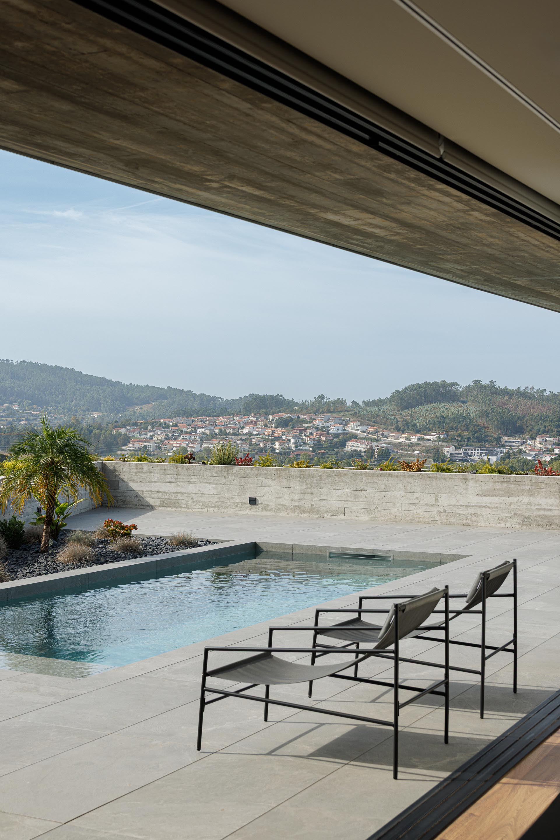 View from beneath the cantilevered roof soffit toward the swimming pool and hillside beyond
