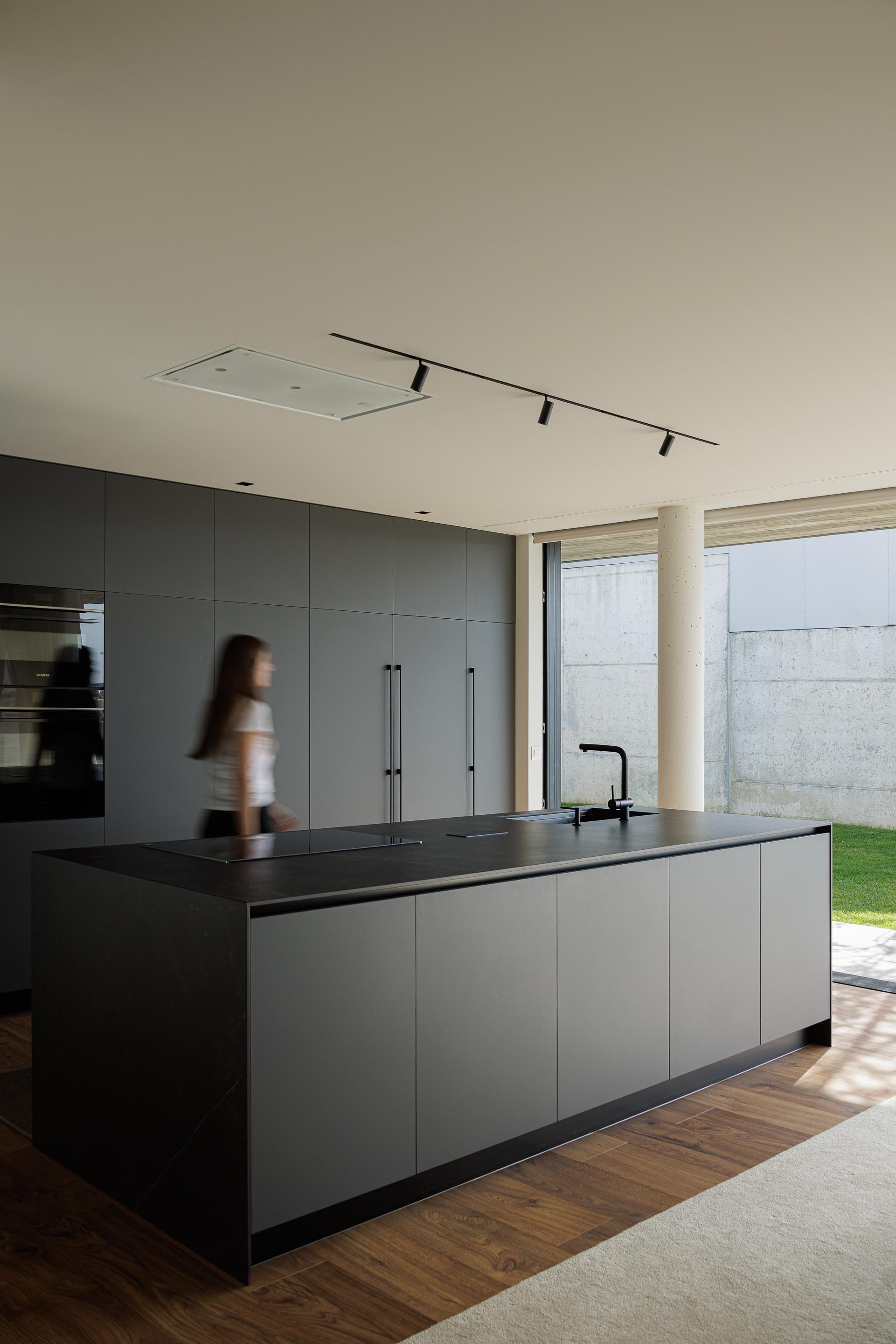 Kitchen island with black countertop as a figure passes through the sunlit space