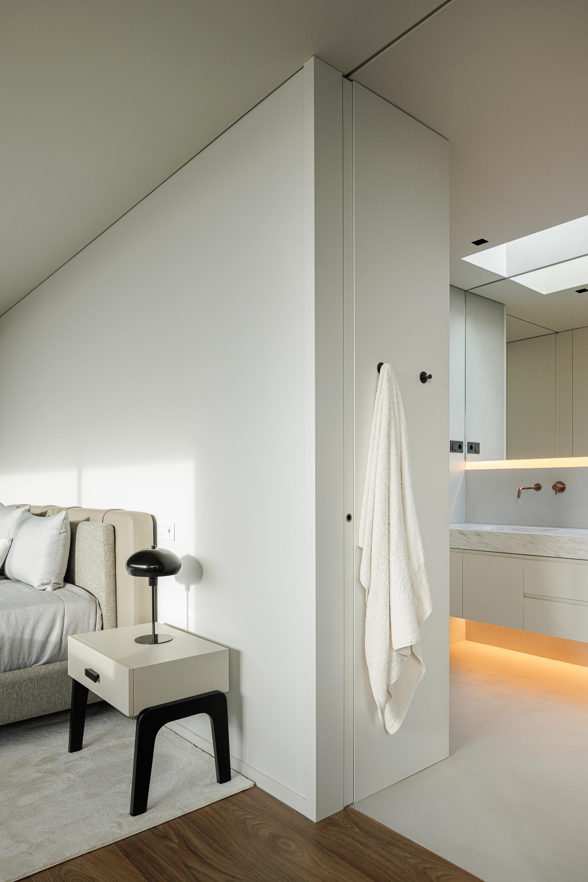 Bedroom with a free-standing partition separating the sleeping area from the ensuite bathroom beyond