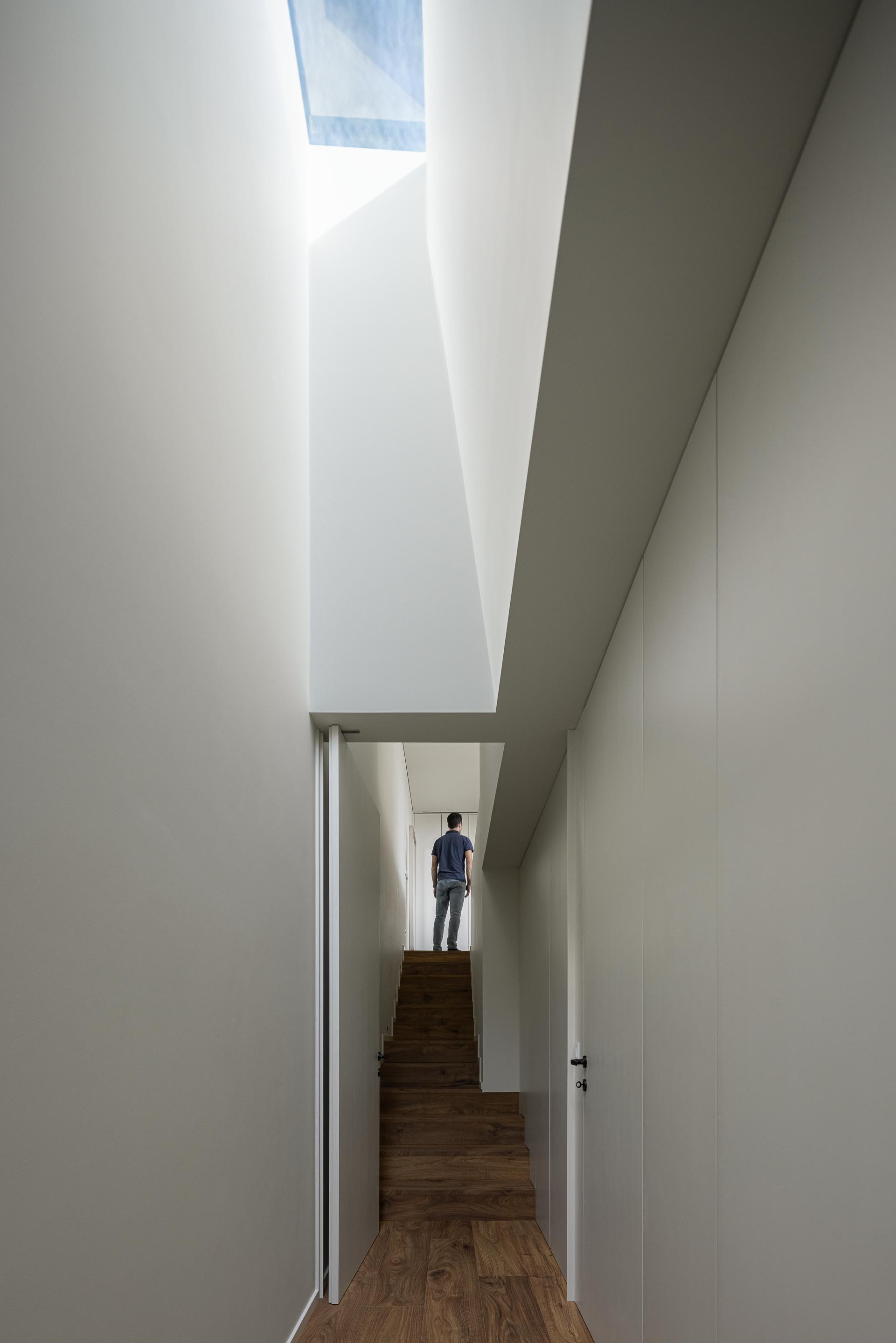Corridor with a skylight above timber stairs and a figure standing in the landing beyond