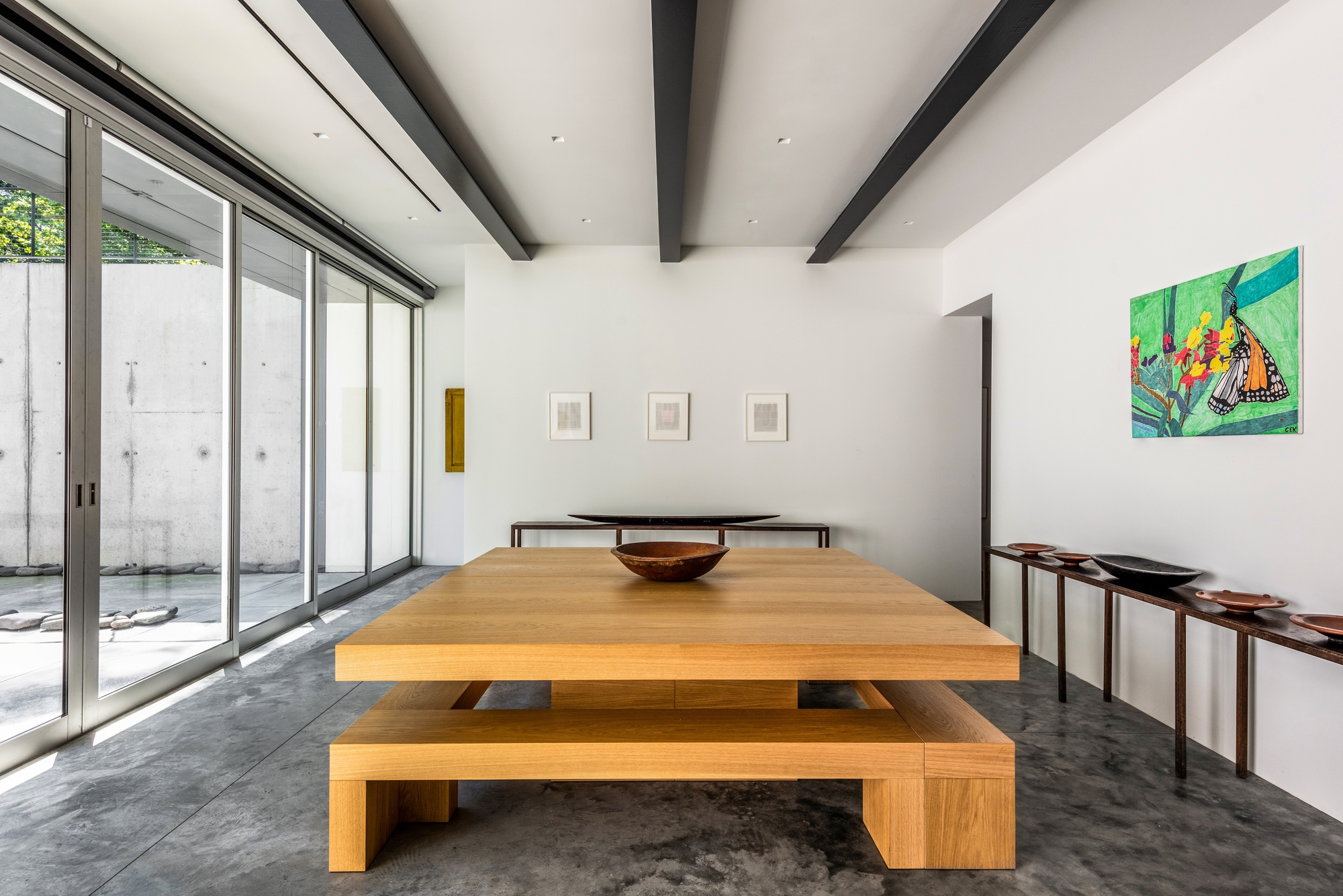 Dining room with timber table and benches on polished concrete floor beneath exposed black beams